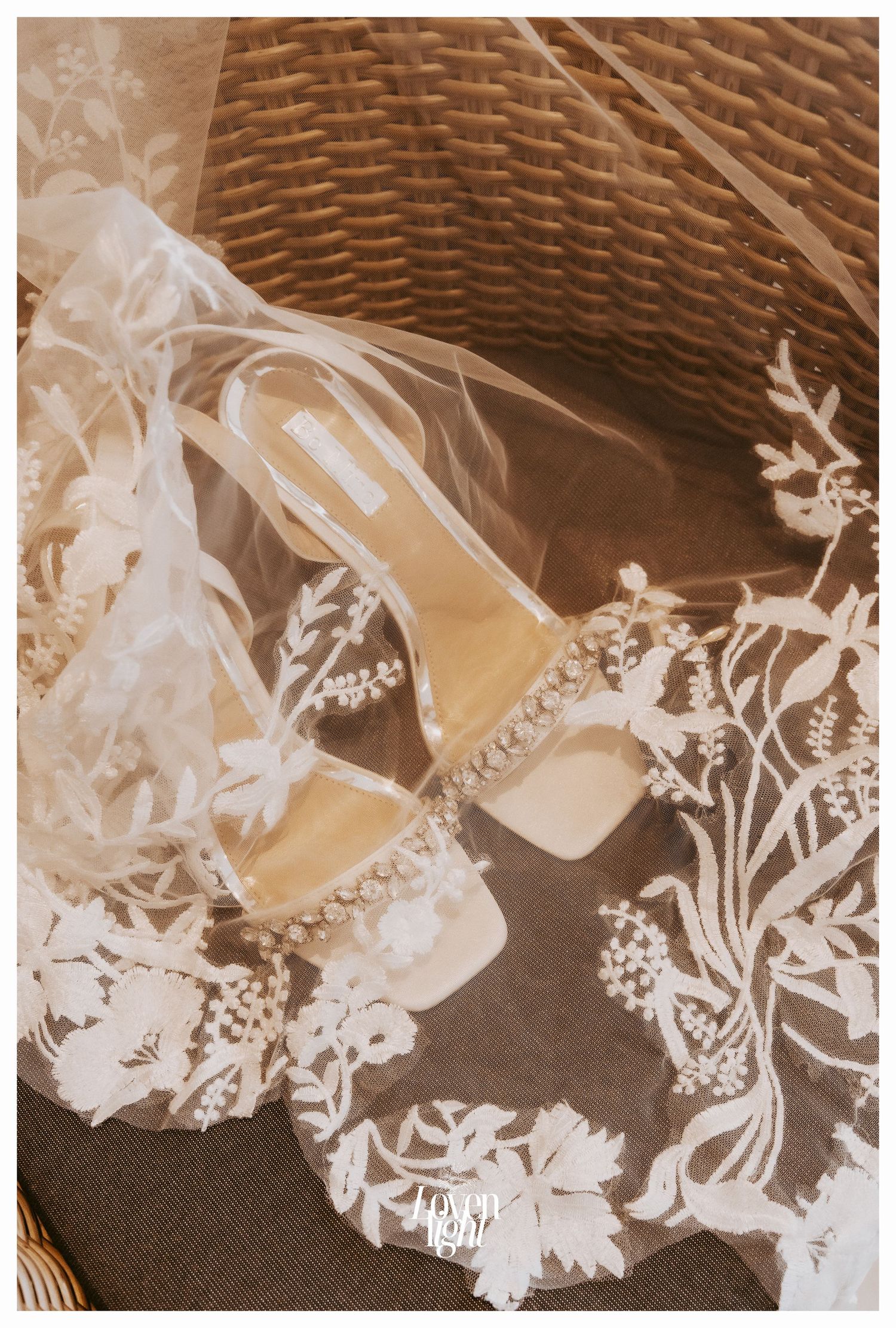 Delicate lace wedding shoes with floral details photographed against a woven basket background.