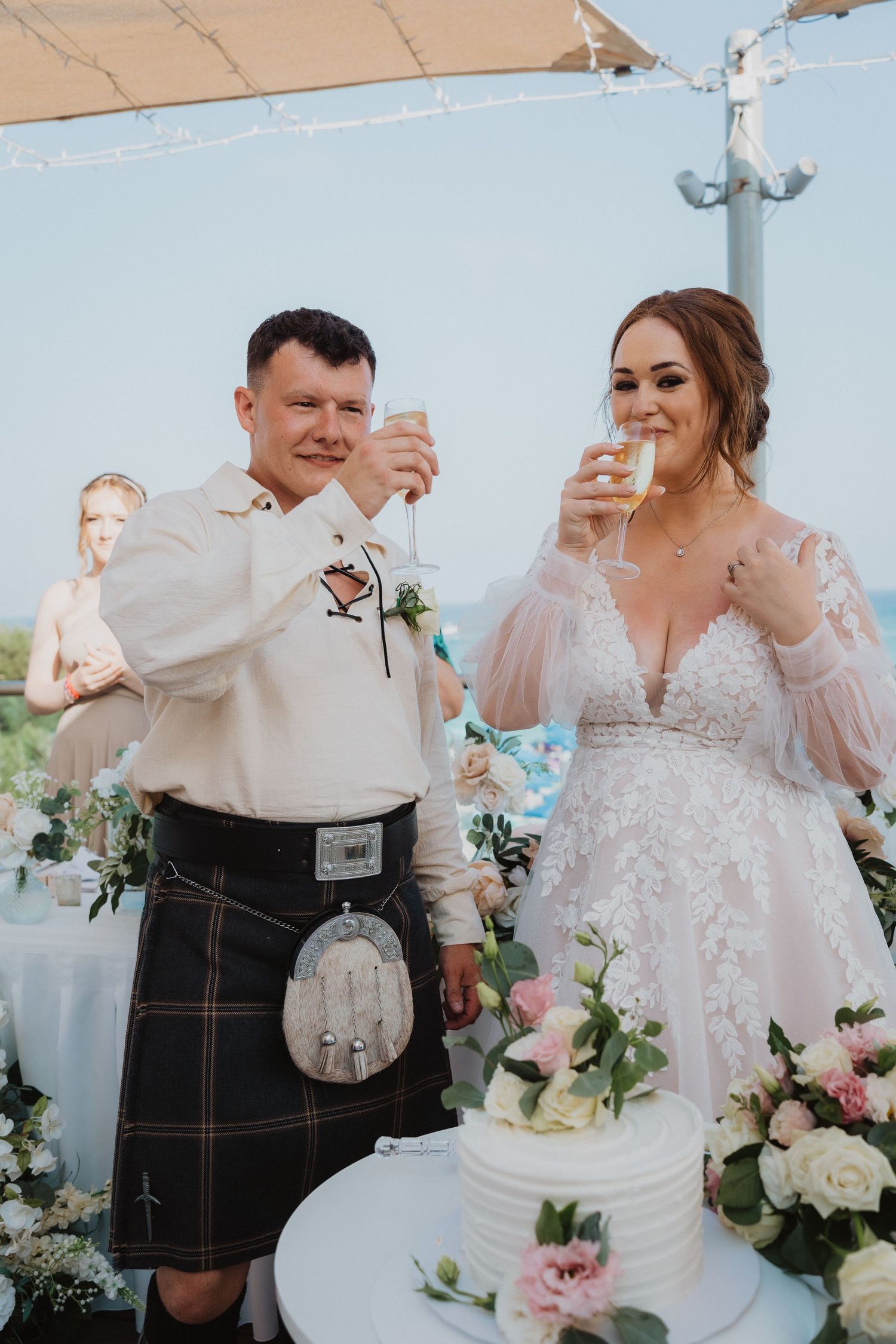 Newlyweds sharing a celebratory toast beside their wedding cake.