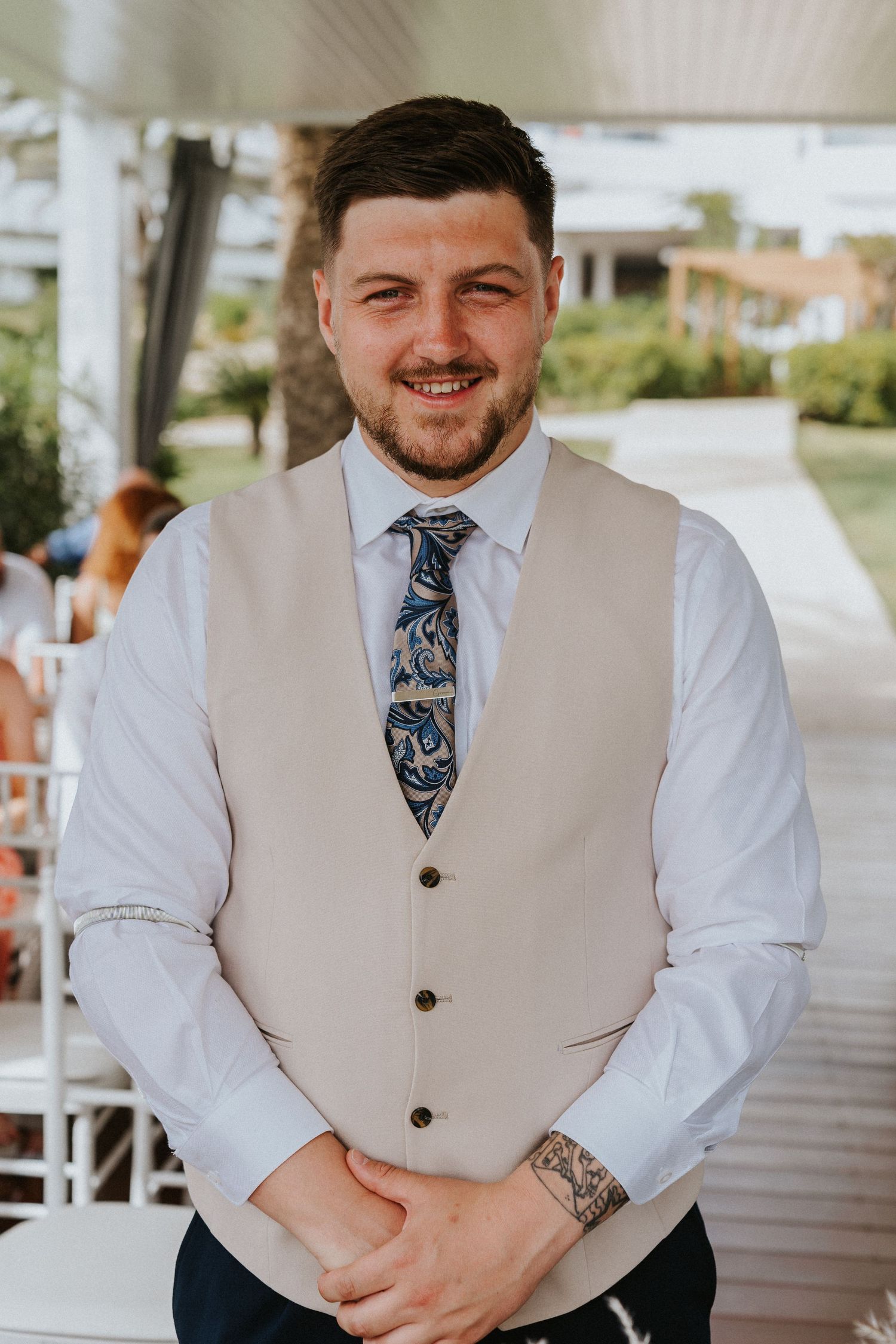 Elegant groomsman wearing a beige vest and patterned tie.