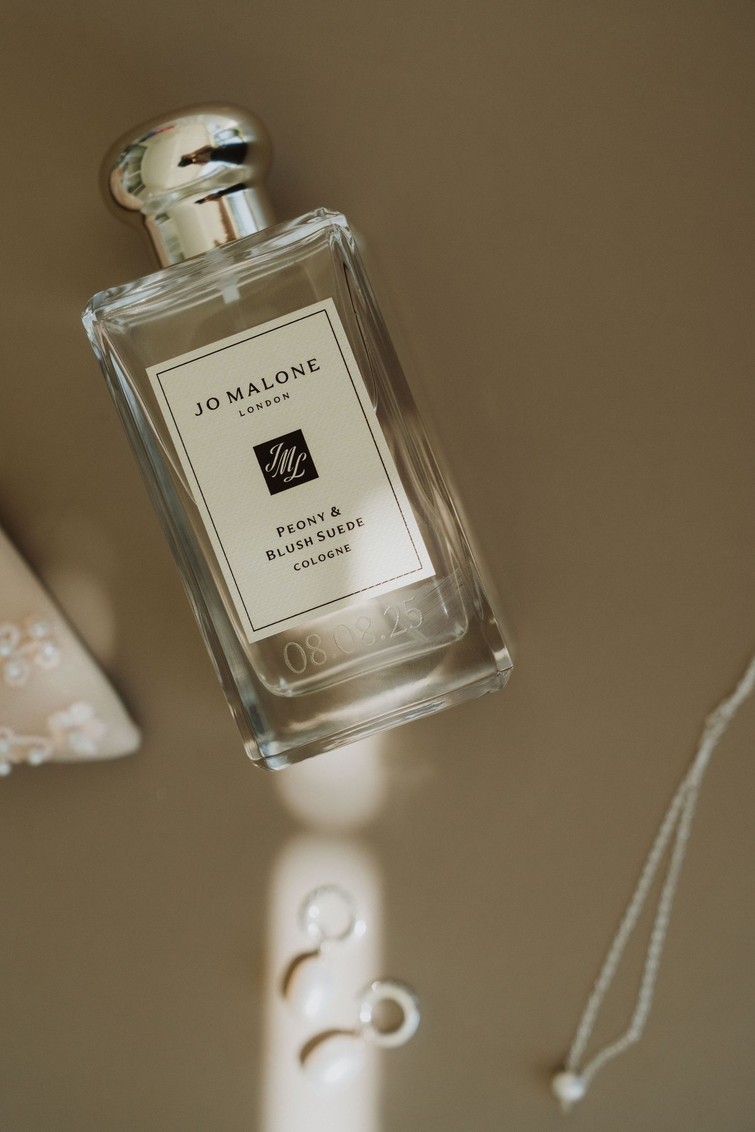 A series of Jo Malone London perfume bottles photographed in soft, warm lighting against a neutral beige background.