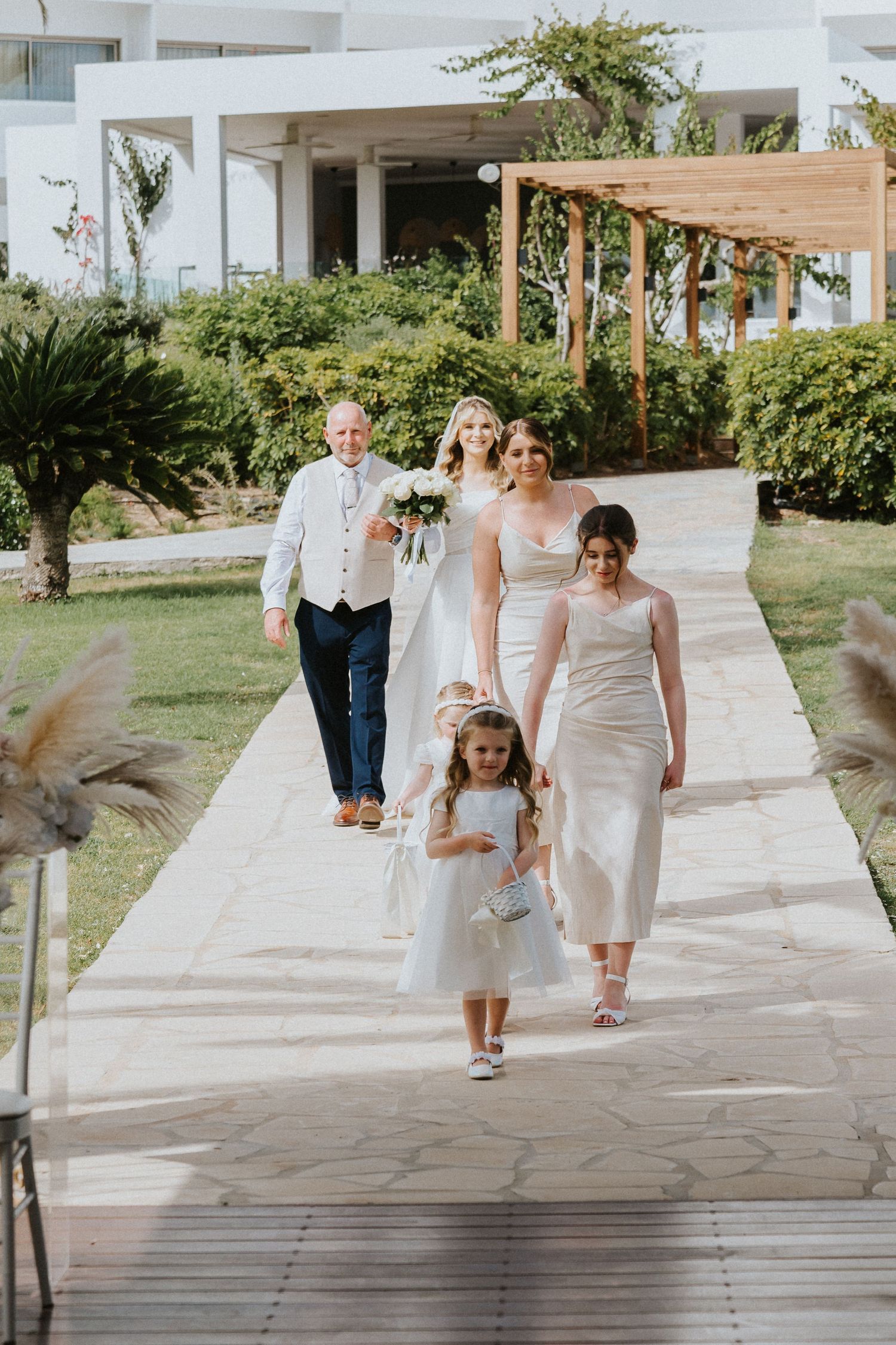 Wedding party members walking down a stone pathway surrounded by tropical gardens.
