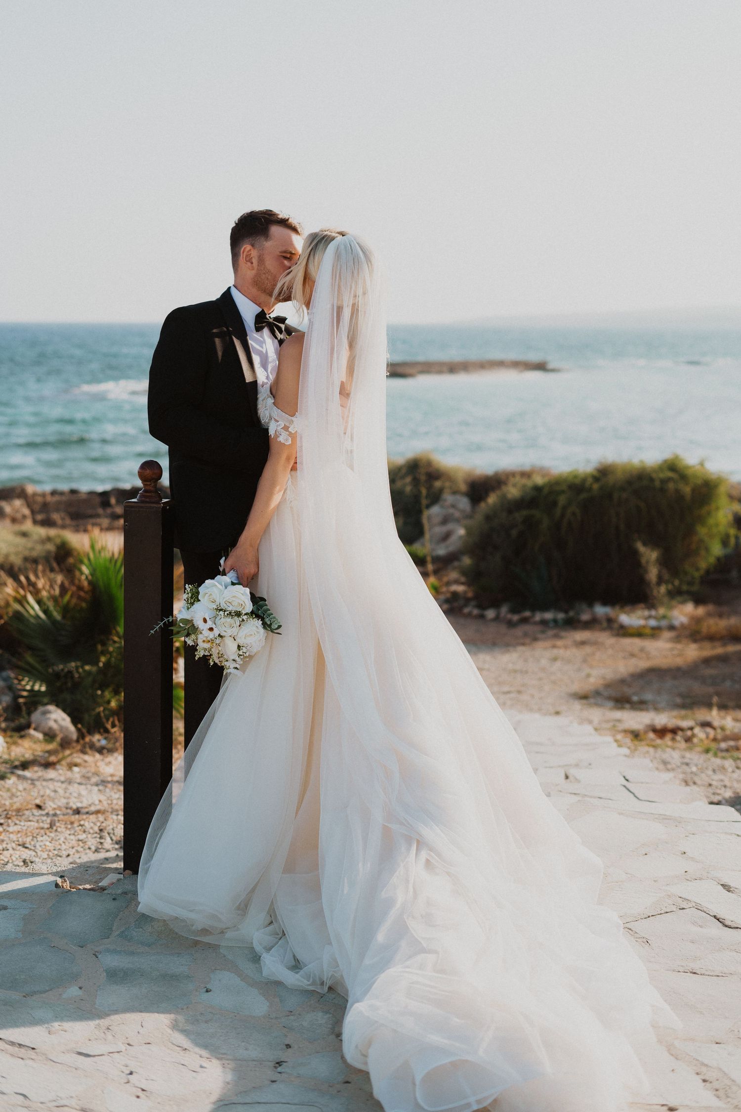 Elegant coastal wedding portrait with flowing veil and ocean views.