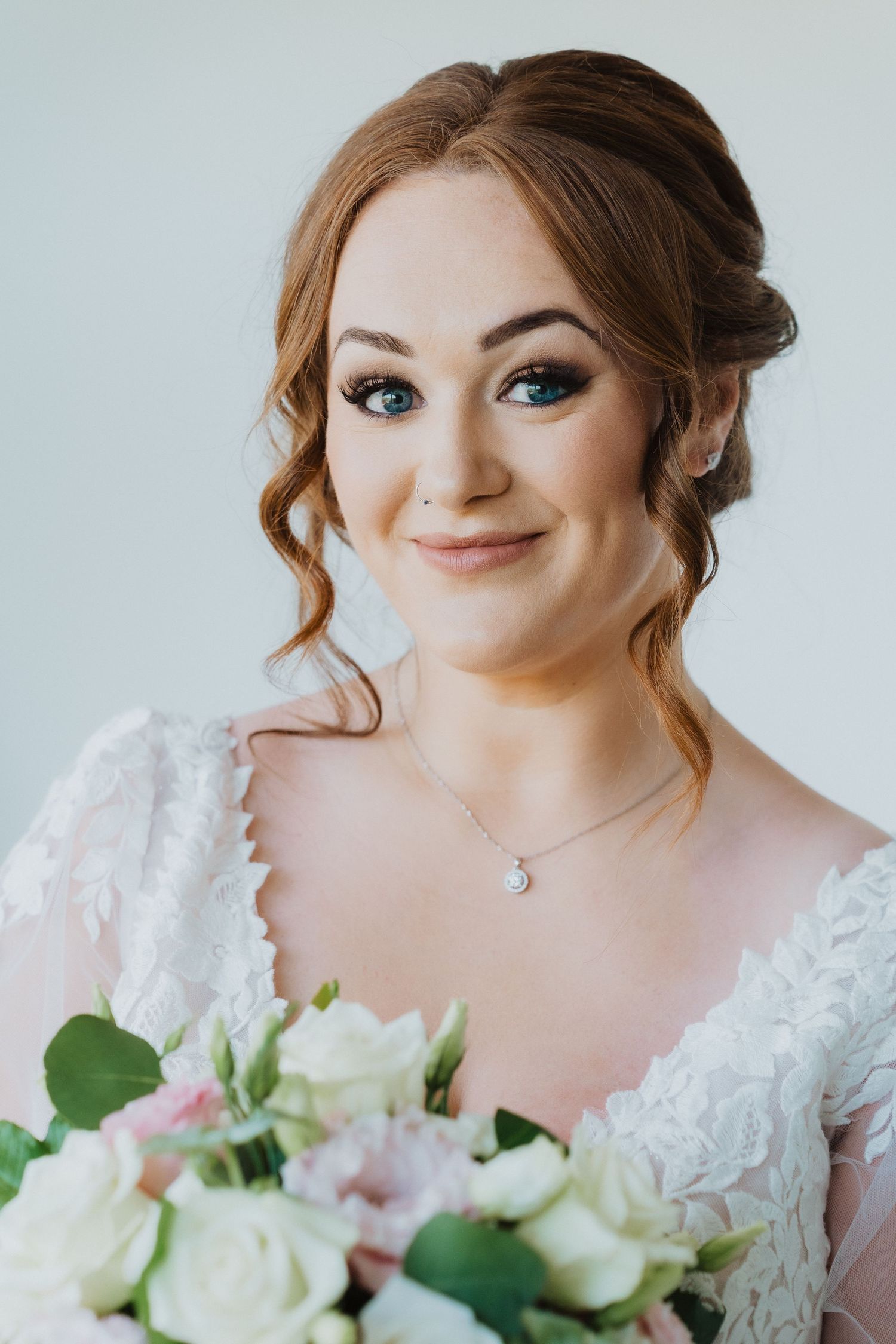 Wedding portrait of bride and guest in emerald green dress standing together in bright room.