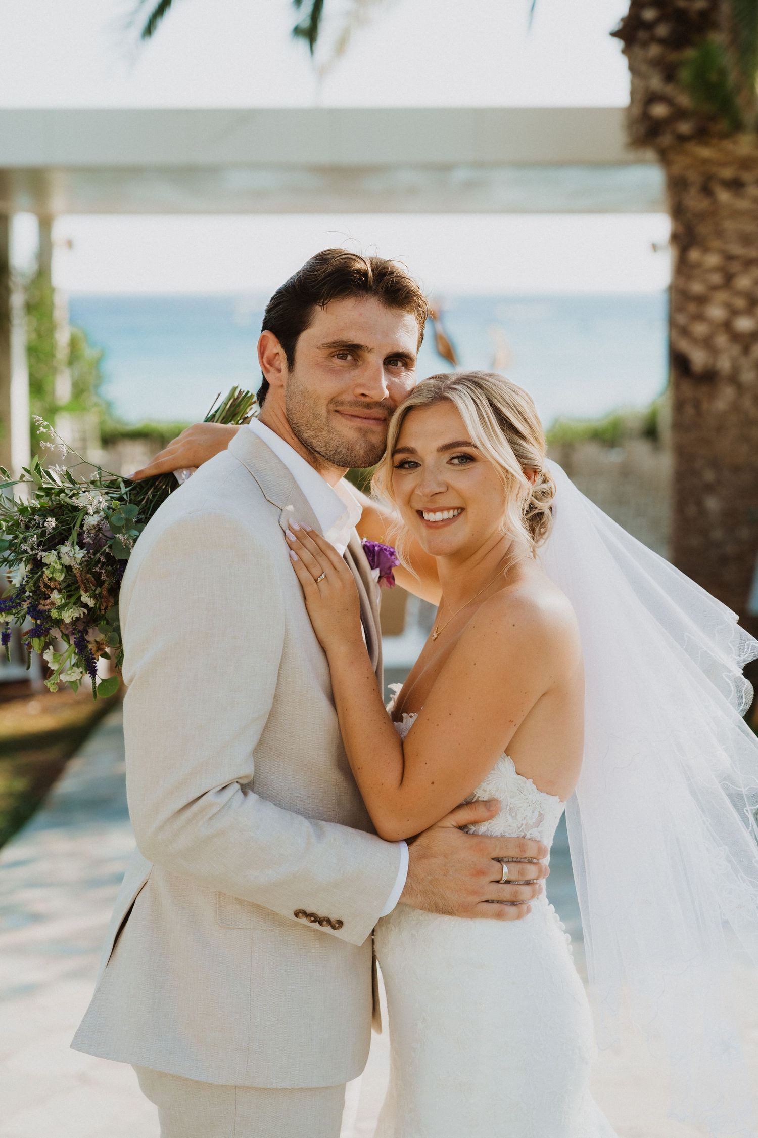 Romantic wedding couple shares intimate moments in a tropical outdoor setting with palm trees.