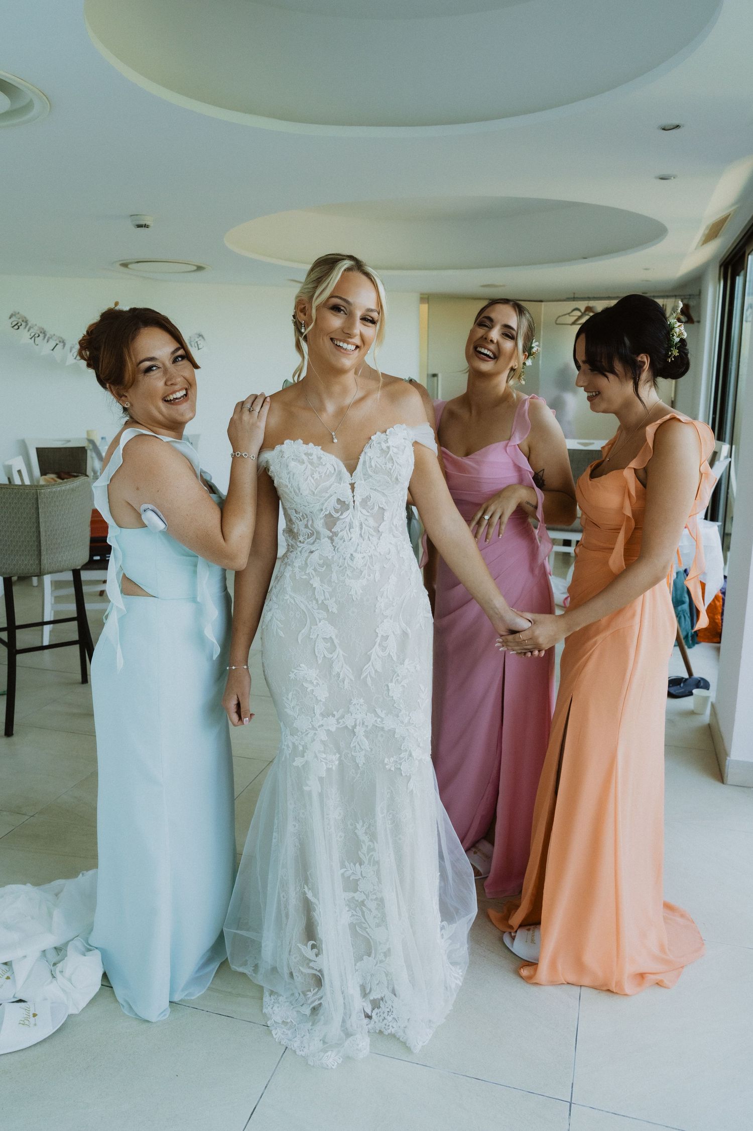 Wedding party getting ready in a modern white room with various colored dresses.