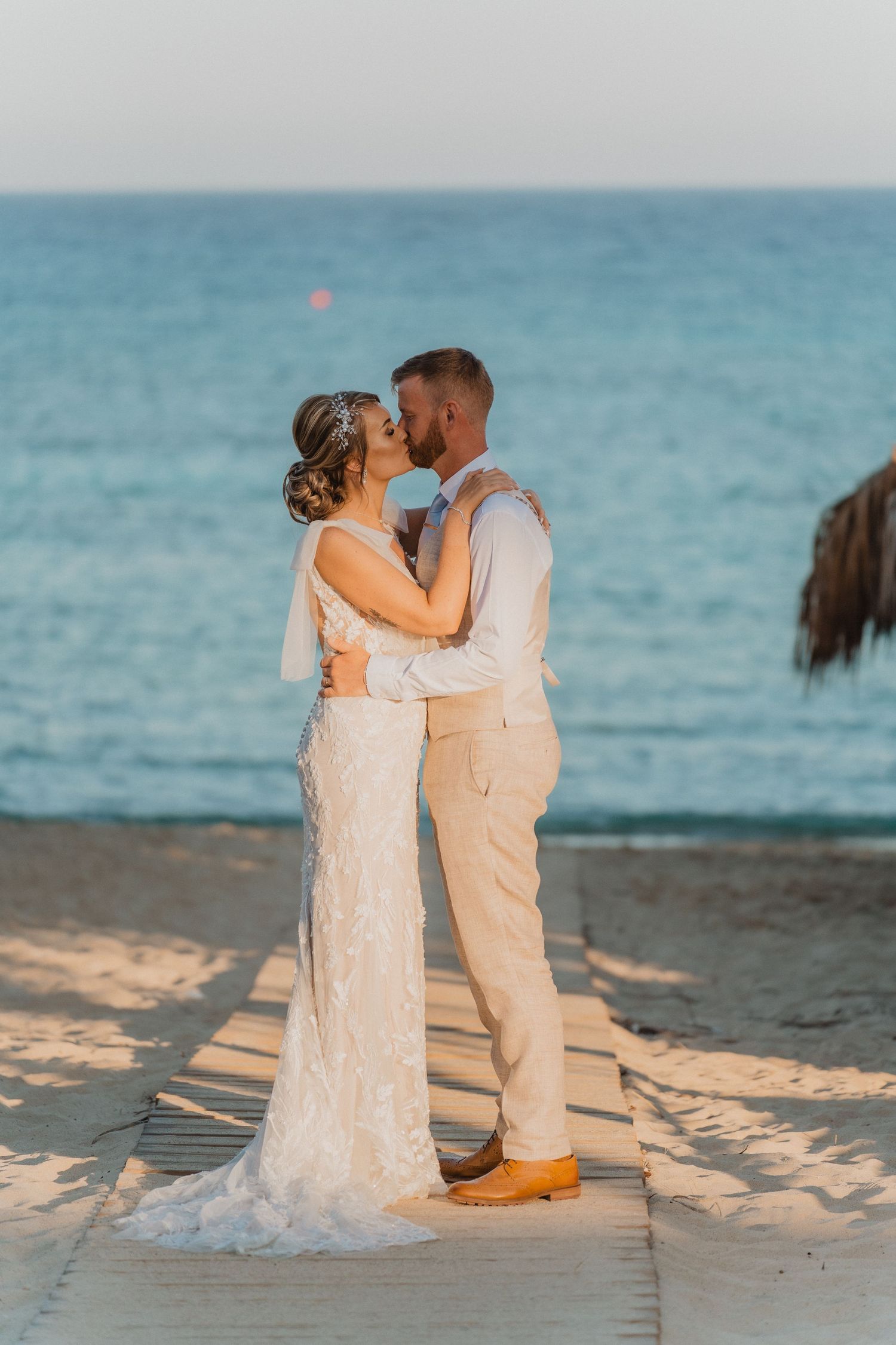 Romantic beach wedding portraits on wooden walkway at sunset.