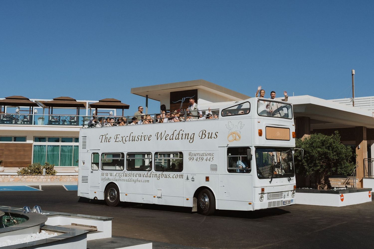 Row of white tour buses parked at a desert rest stop with mountains visible in the background.