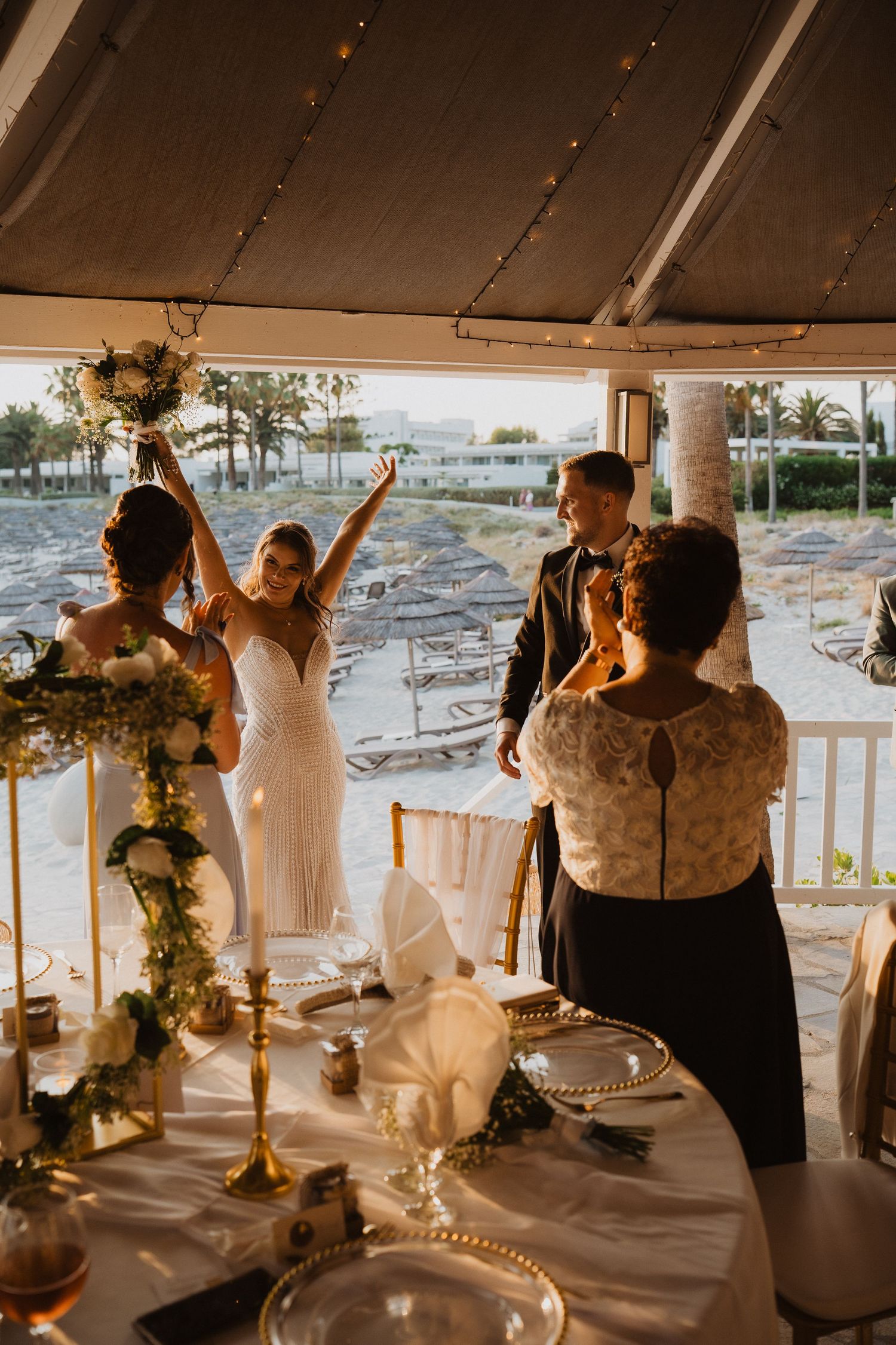Bride and groom making a grand entrance into their wedding reception tent with glowing candles and floral centerpieces.