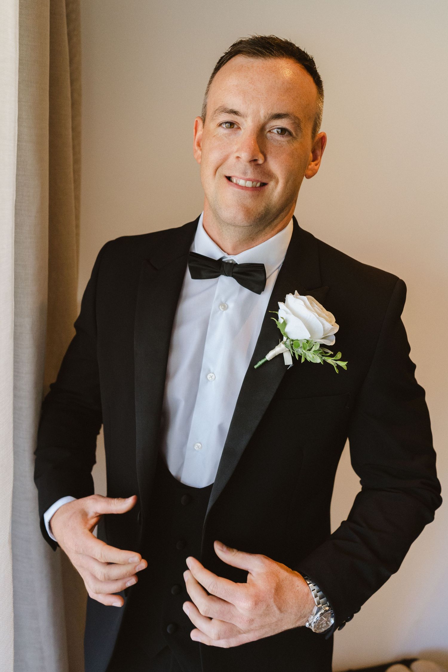 Wedding party member in black tuxedo and bow tie poses with animated expressions.