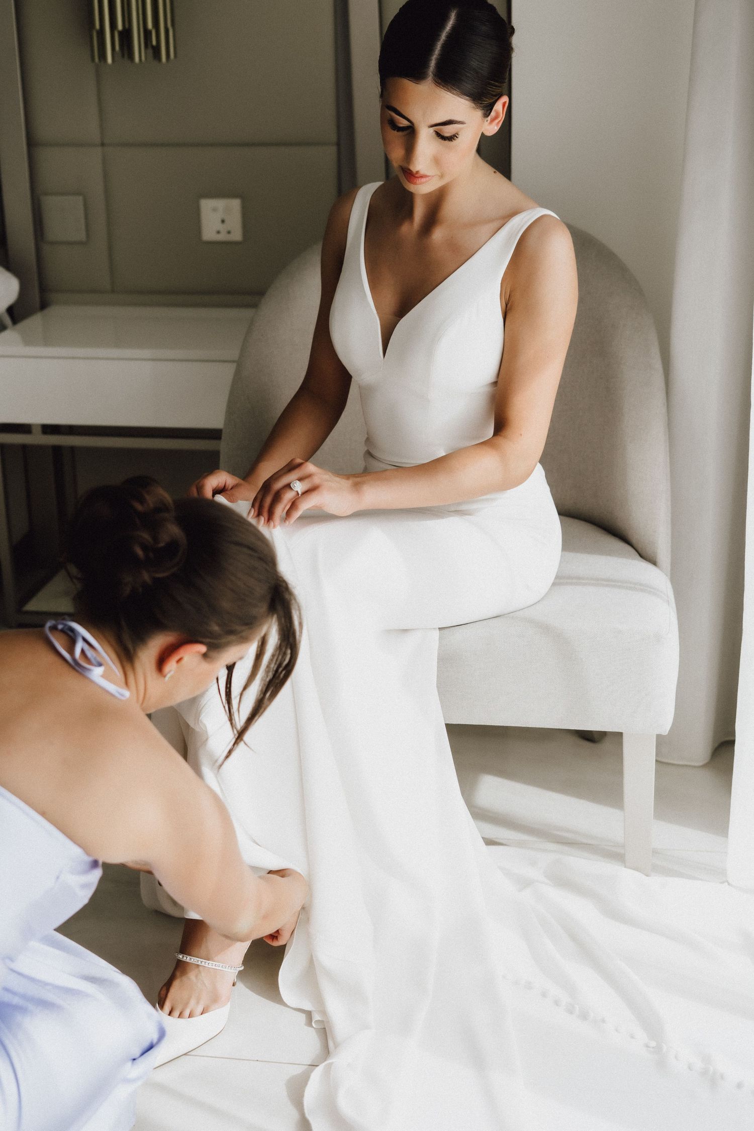 Wedding dress preparation scene with final adjustments being made in an intimate setting.