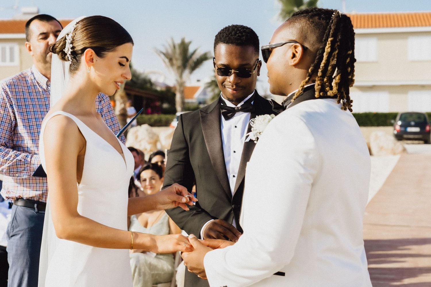 Couple exchanging vows during an outdoor wedding ceremony on a sunny day by the ocean.