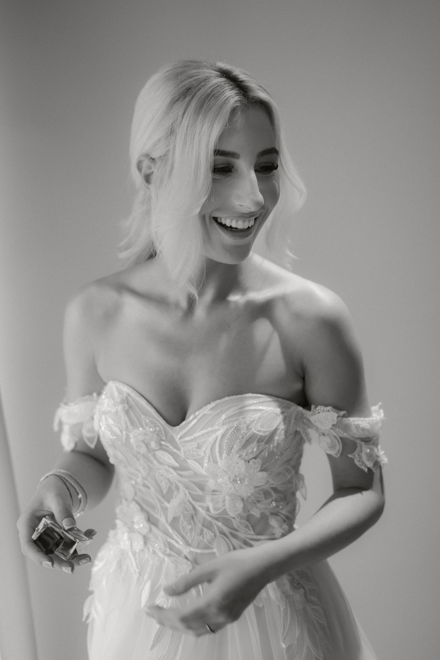Black and white candid portrait capturing joyful laughter in a wedding dress.
