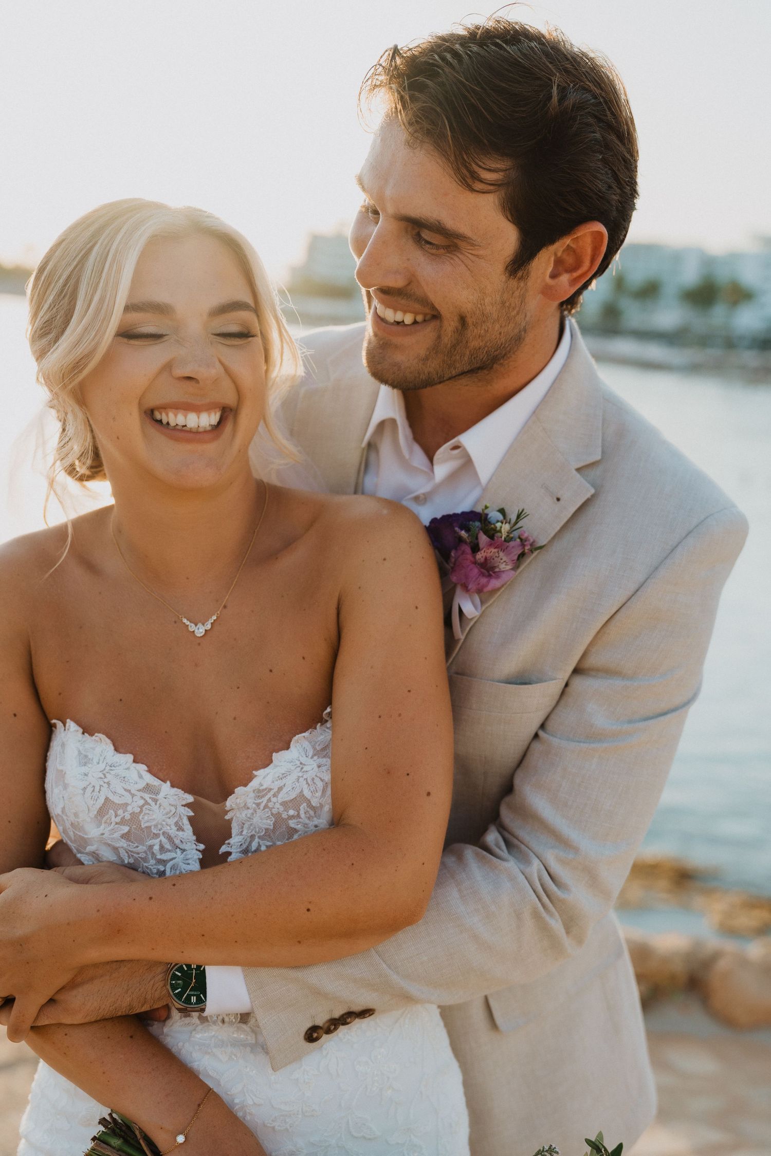 Romantic beachside wedding photos capture joyful laughter between couple against ocean backdrop.