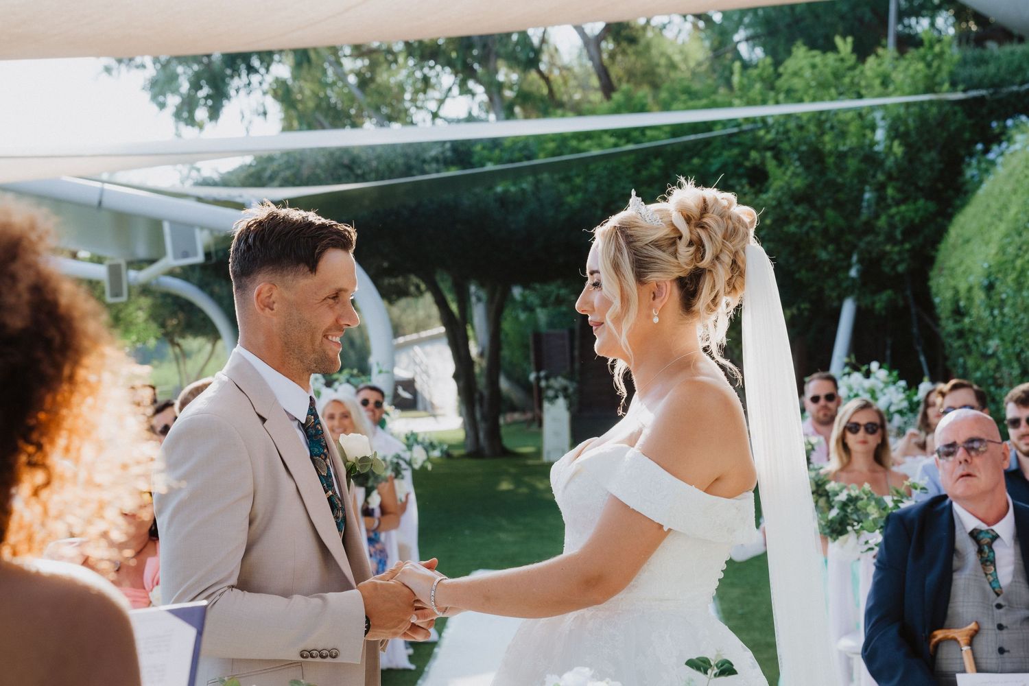 A wedding ceremony moment under a covered outdoor venue with white floral arrangements.