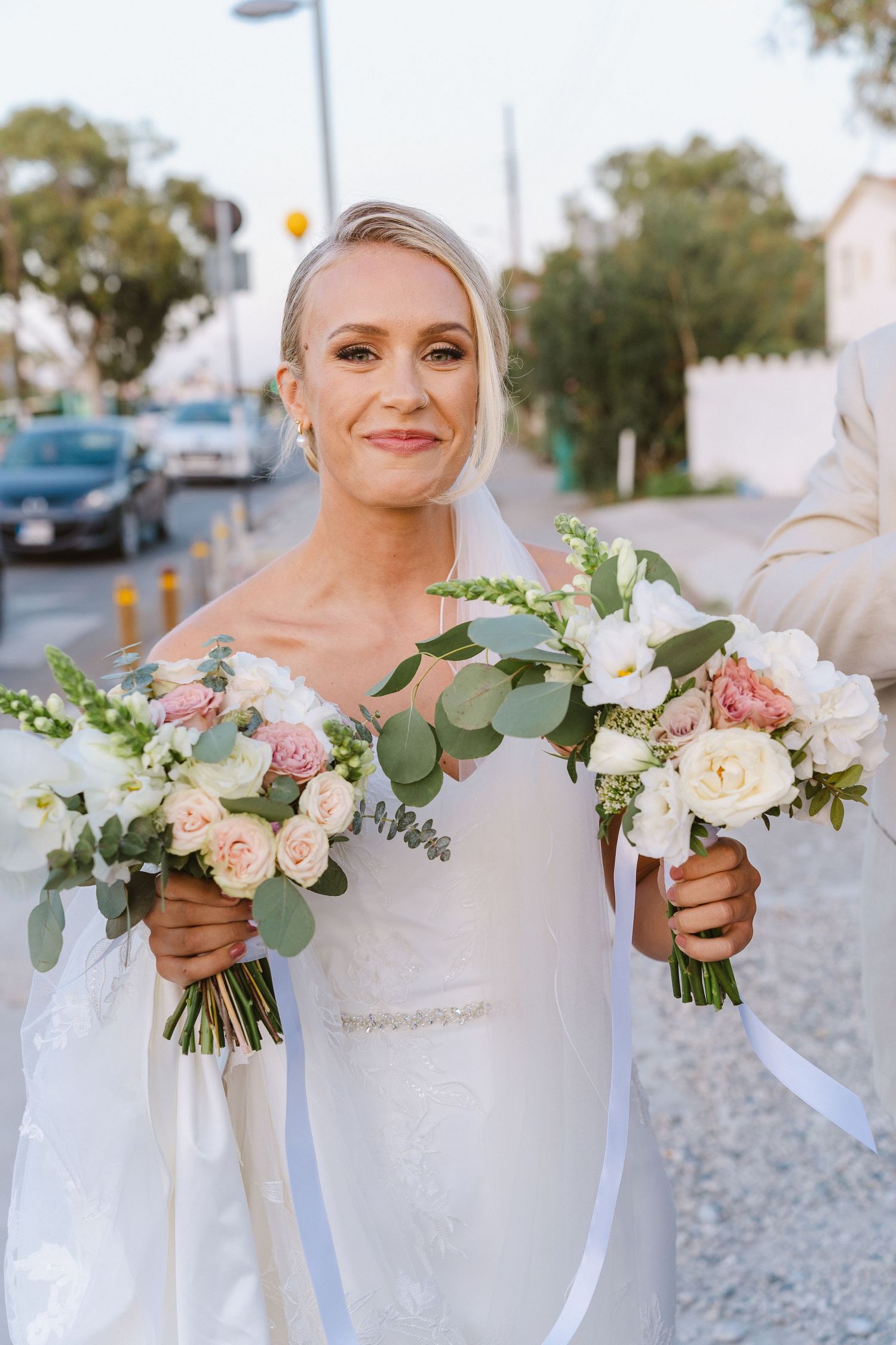 A bride holds two elegant bouquets featuring blush roses, white flowers and eucalyptus on her wedding day.