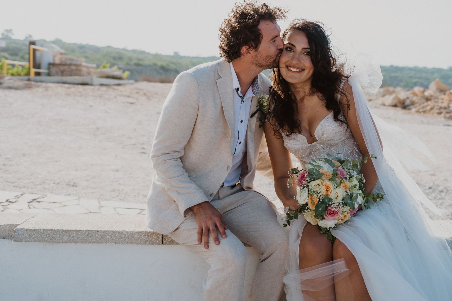 A loving couple shares laughter during their coastal wedding photoshoot.