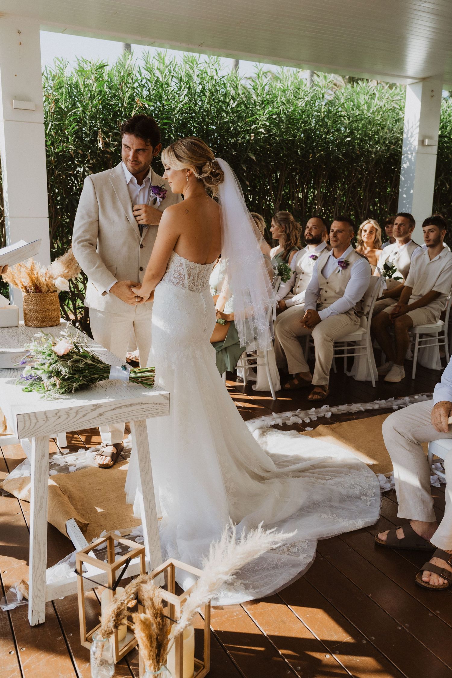 Wedding ceremony setup with wooden chairs and floral decorations under a covered outdoor pavilion.