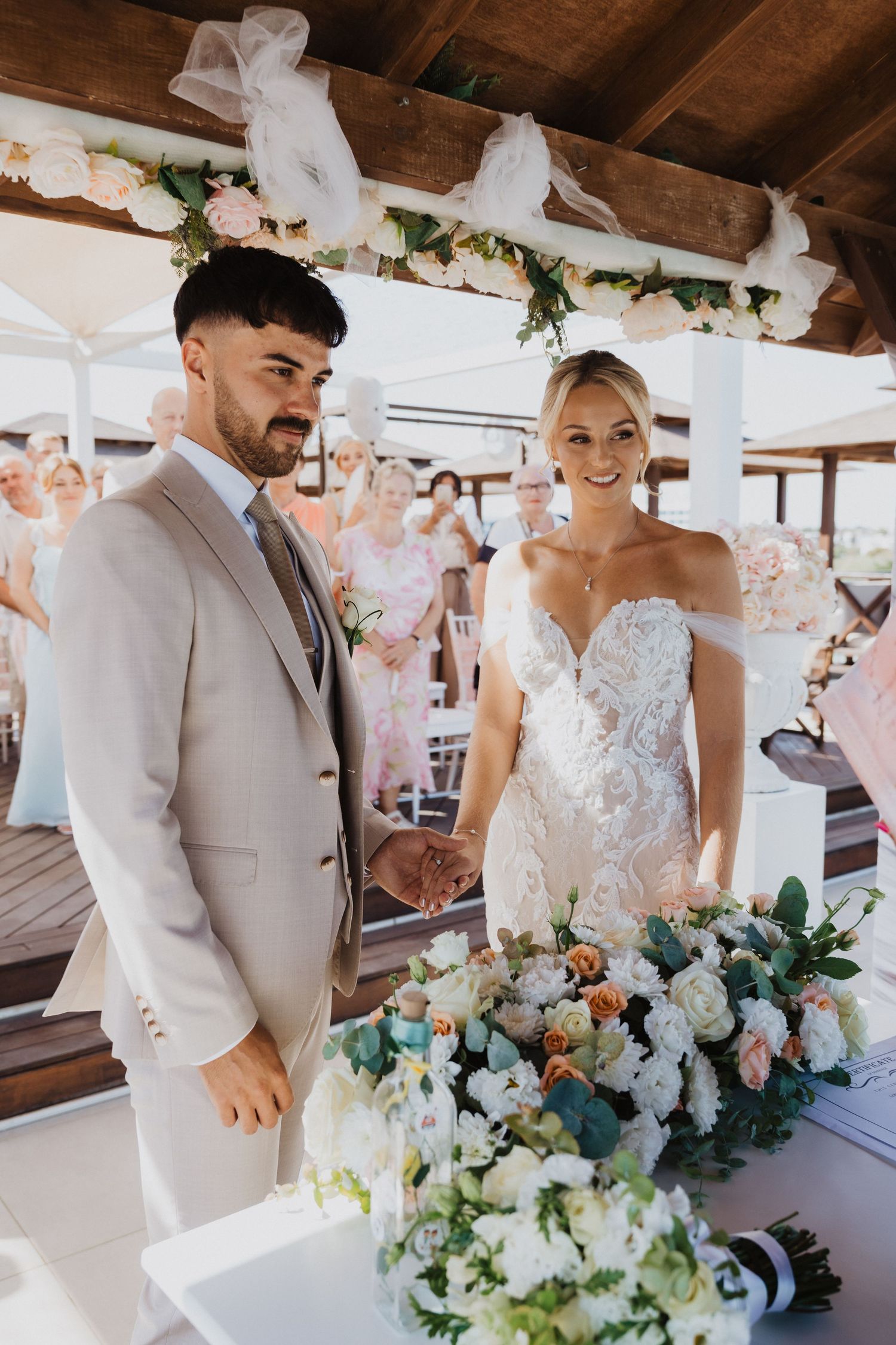 Beautiful white and green floral arrangements decorate a beachside wedding ceremony.