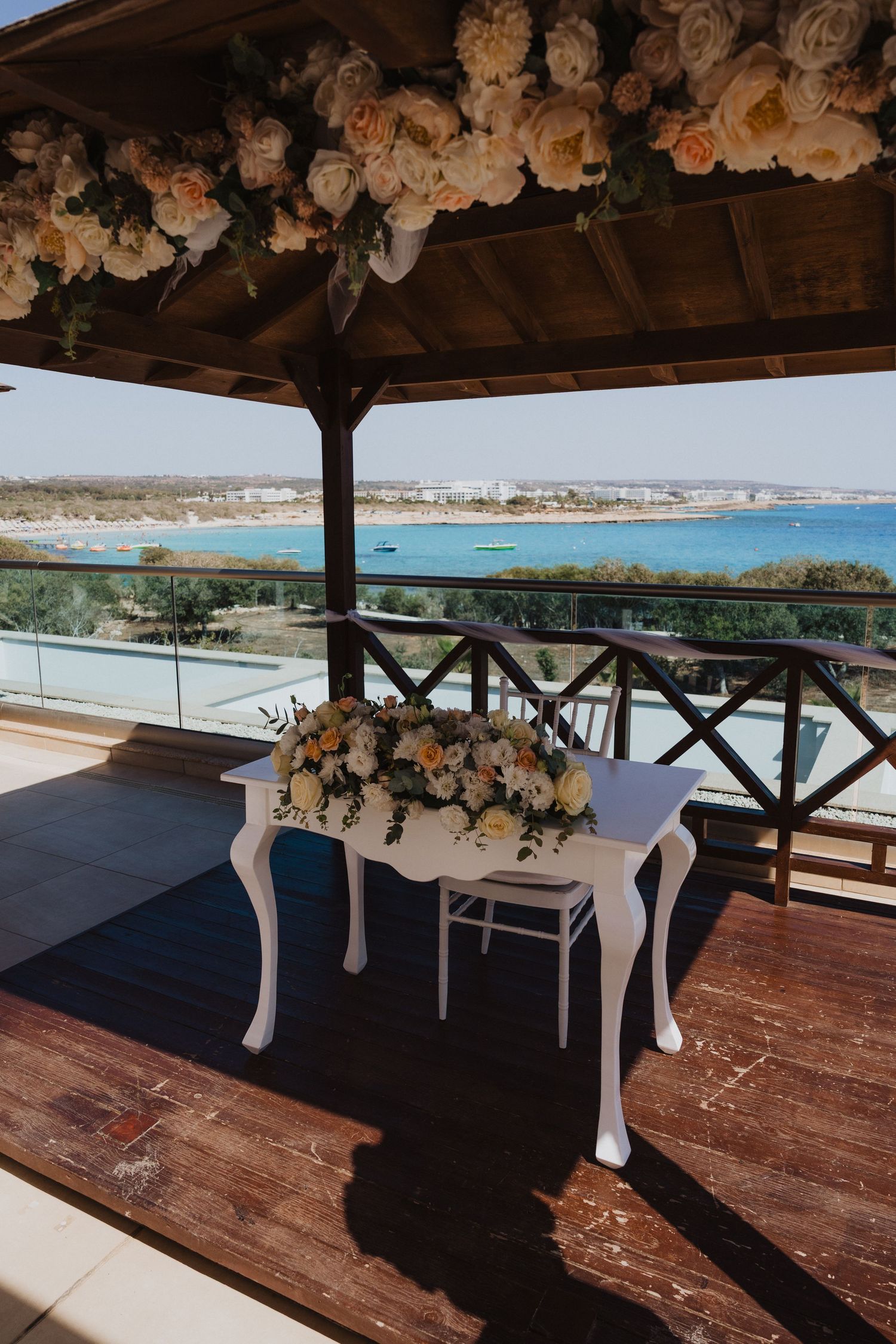 Elegant wedding venue with floral decorations overlooking a beautiful blue ocean bay.