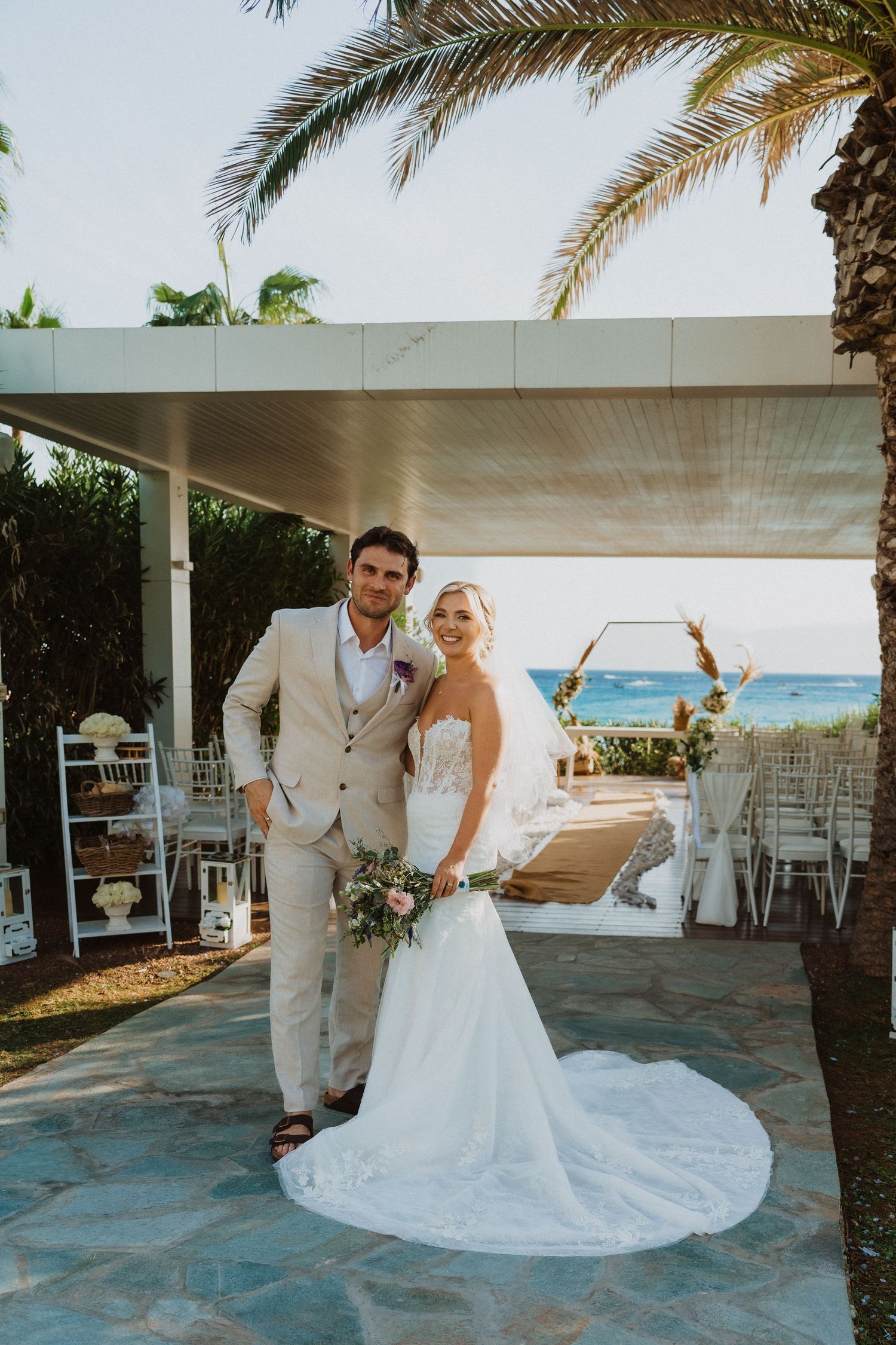 Bride and groom share romantic moments during their beach wedding with palm trees in background.