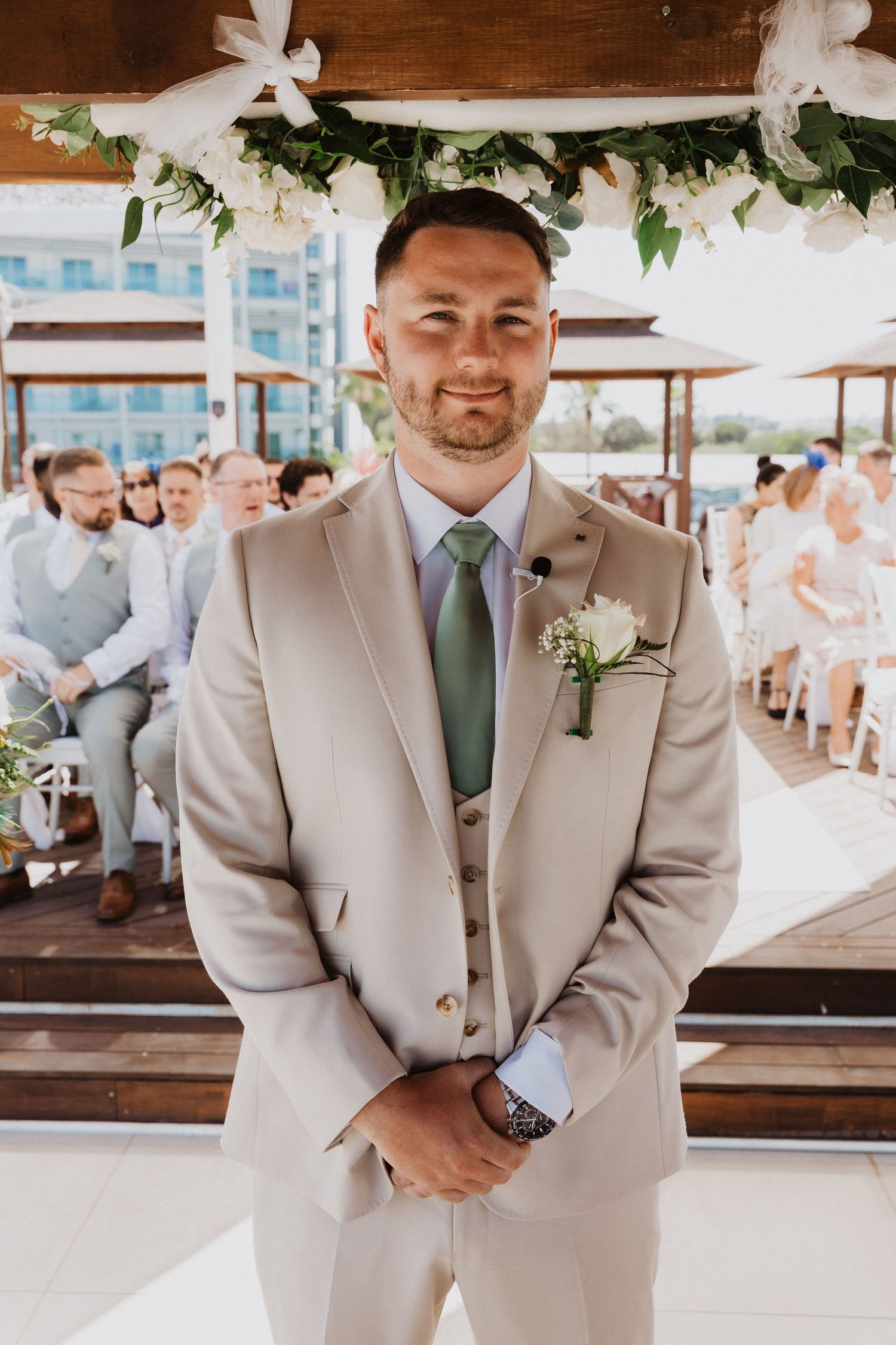 Groomsmen in light beige suits with mint green ties pose during an elegant outdoor wedding celebration.