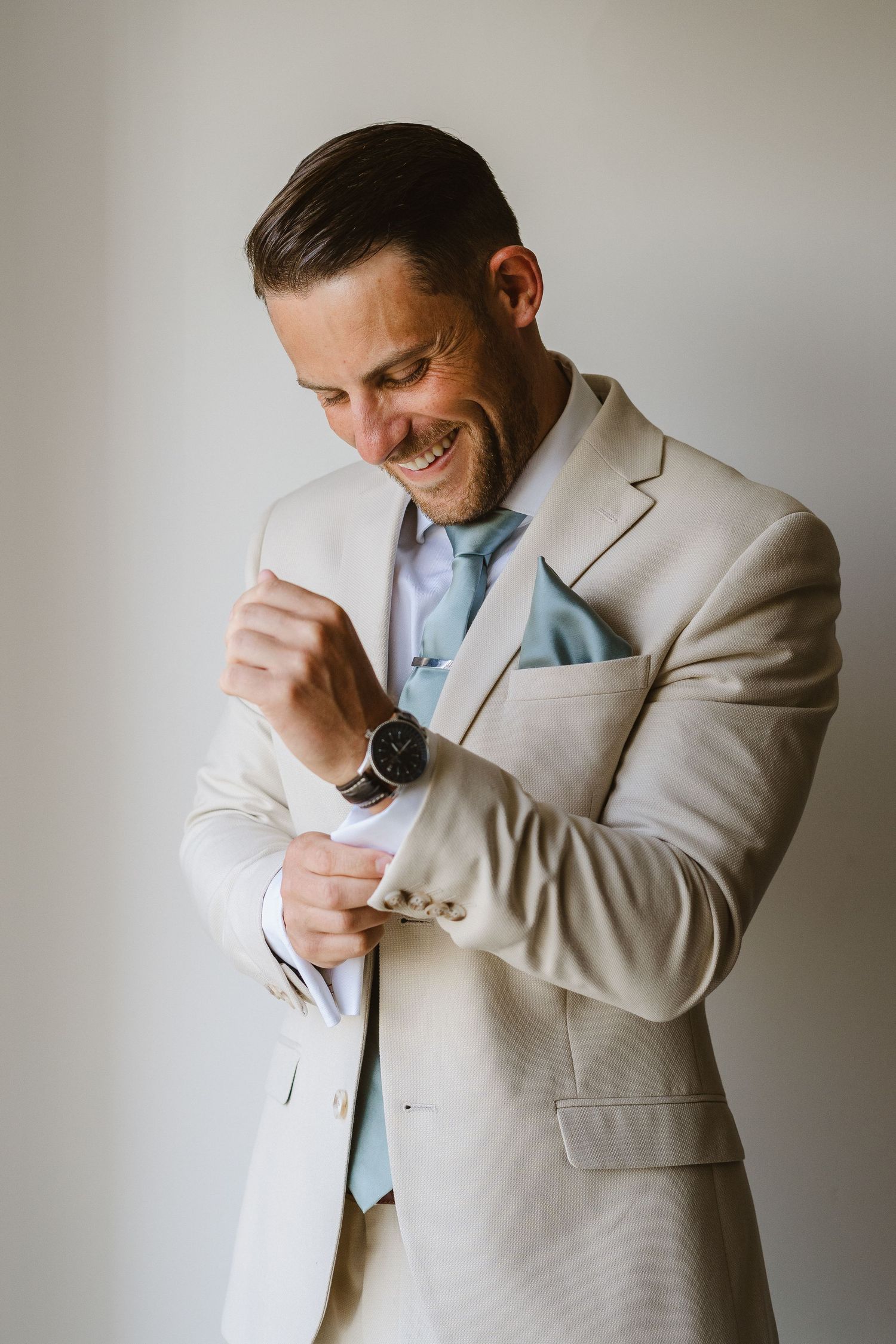 Natural light portrait of someone in formal attire adjusting their cufflinks.