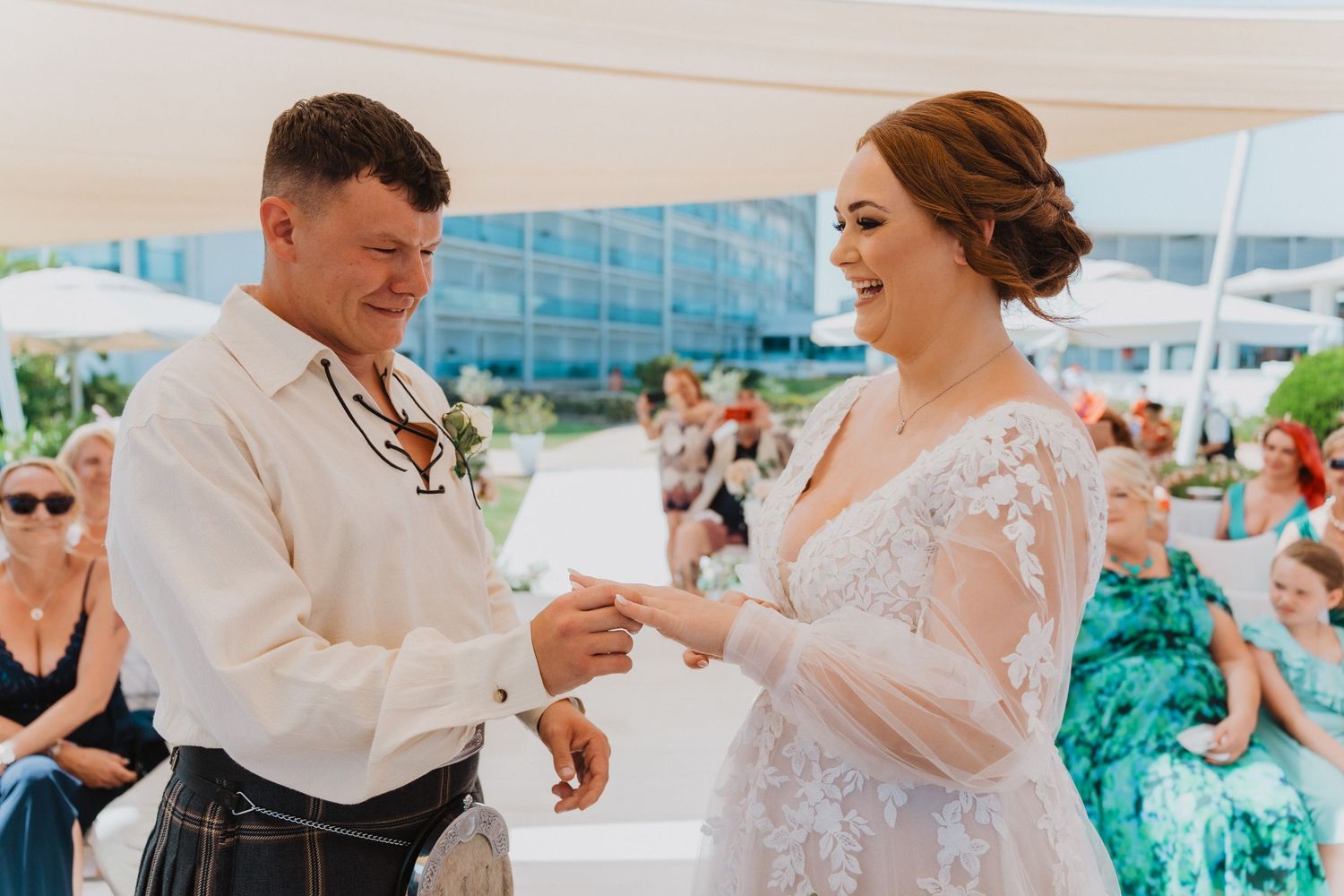 A couple shares a lighthearted moment while exchanging rings at their beach wedding.