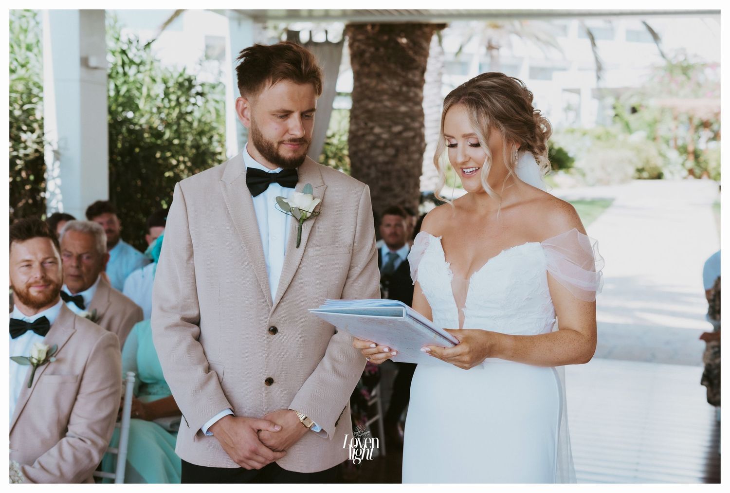 A tender wedding moment captured during an outdoor ceremony with natural greenery backdrop.