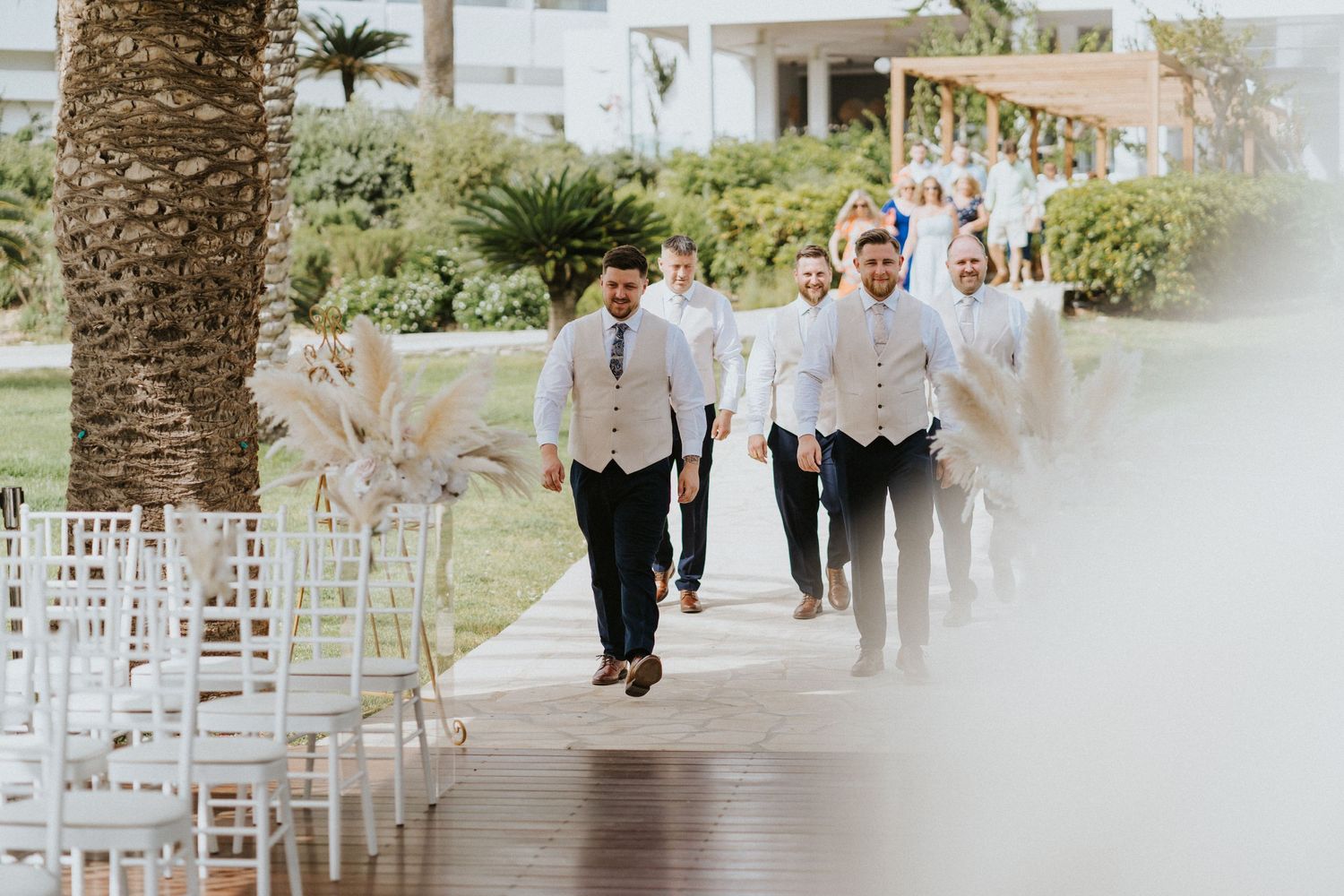 Groomsmen walking down a palm-lined path before the ceremony.