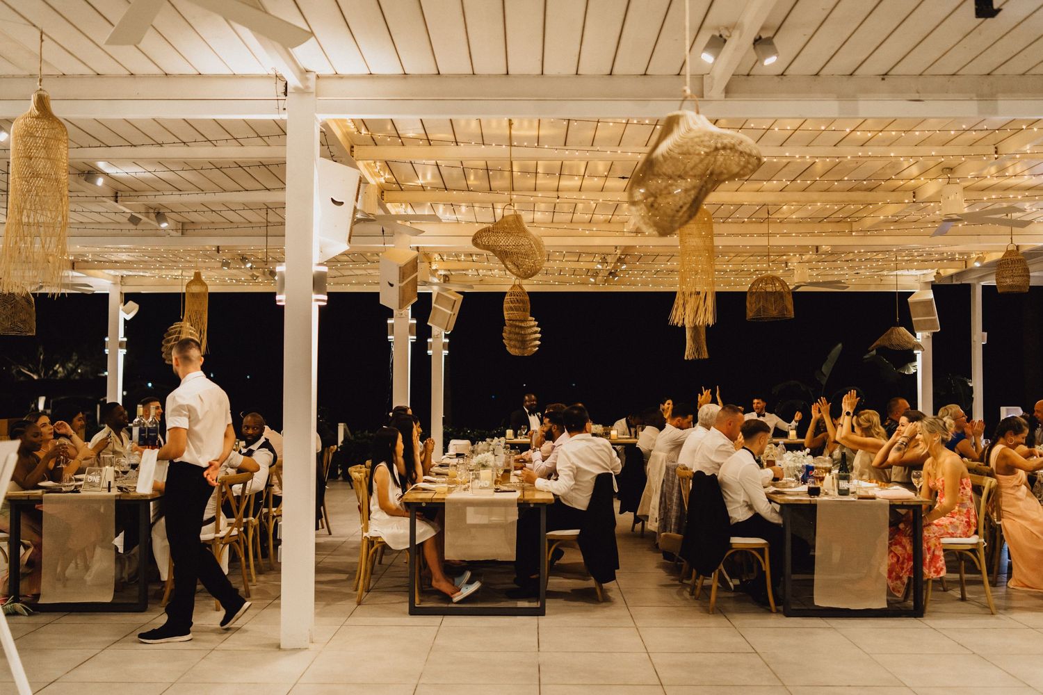 Wedding reception venue with elegant table settings and hanging macrame decor.