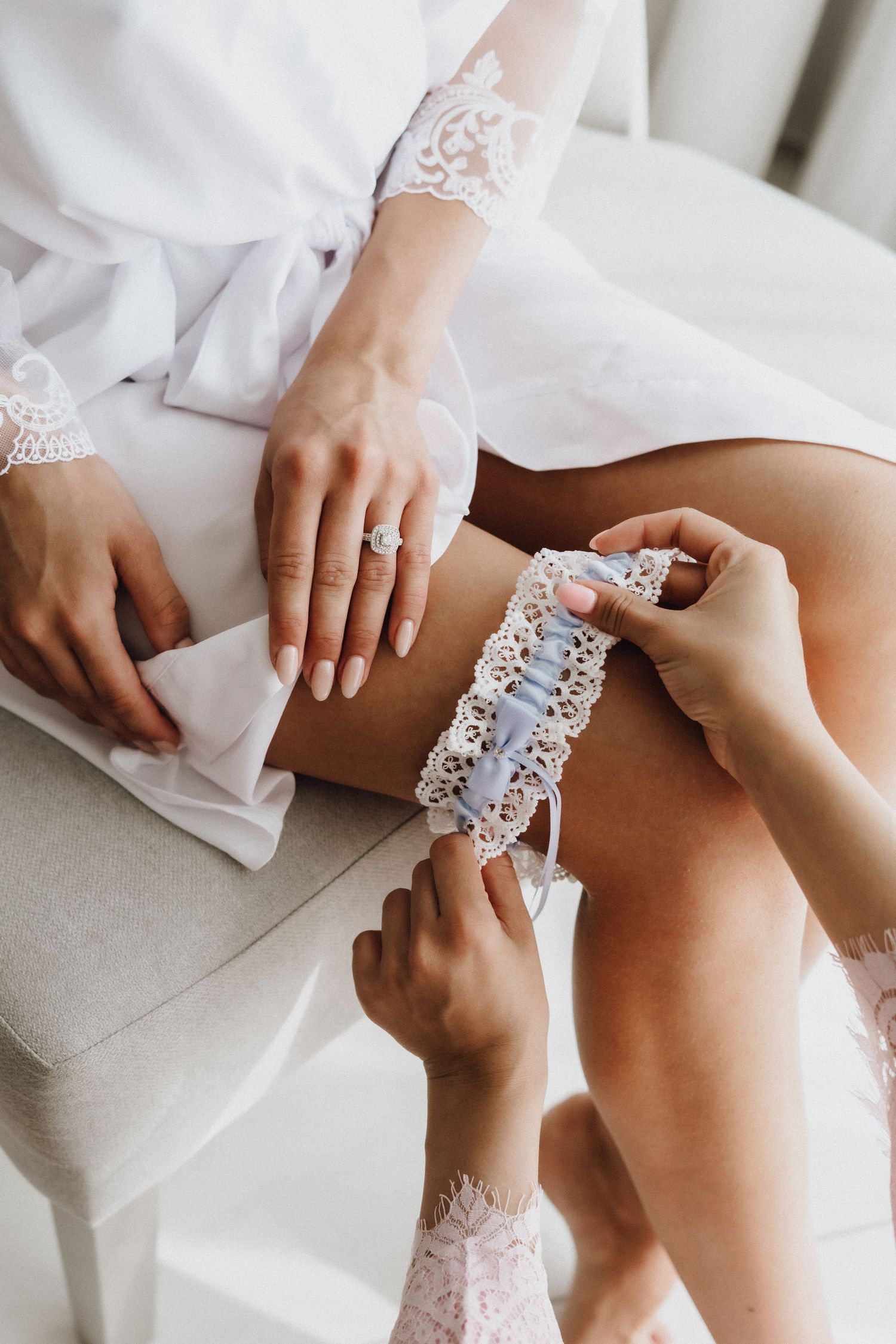 Close up of hands adjusting delicate lace detail on white garment.