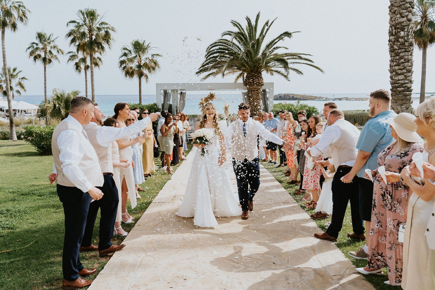 Celebration moment with confetti shower along oceanside wedding ceremony path.