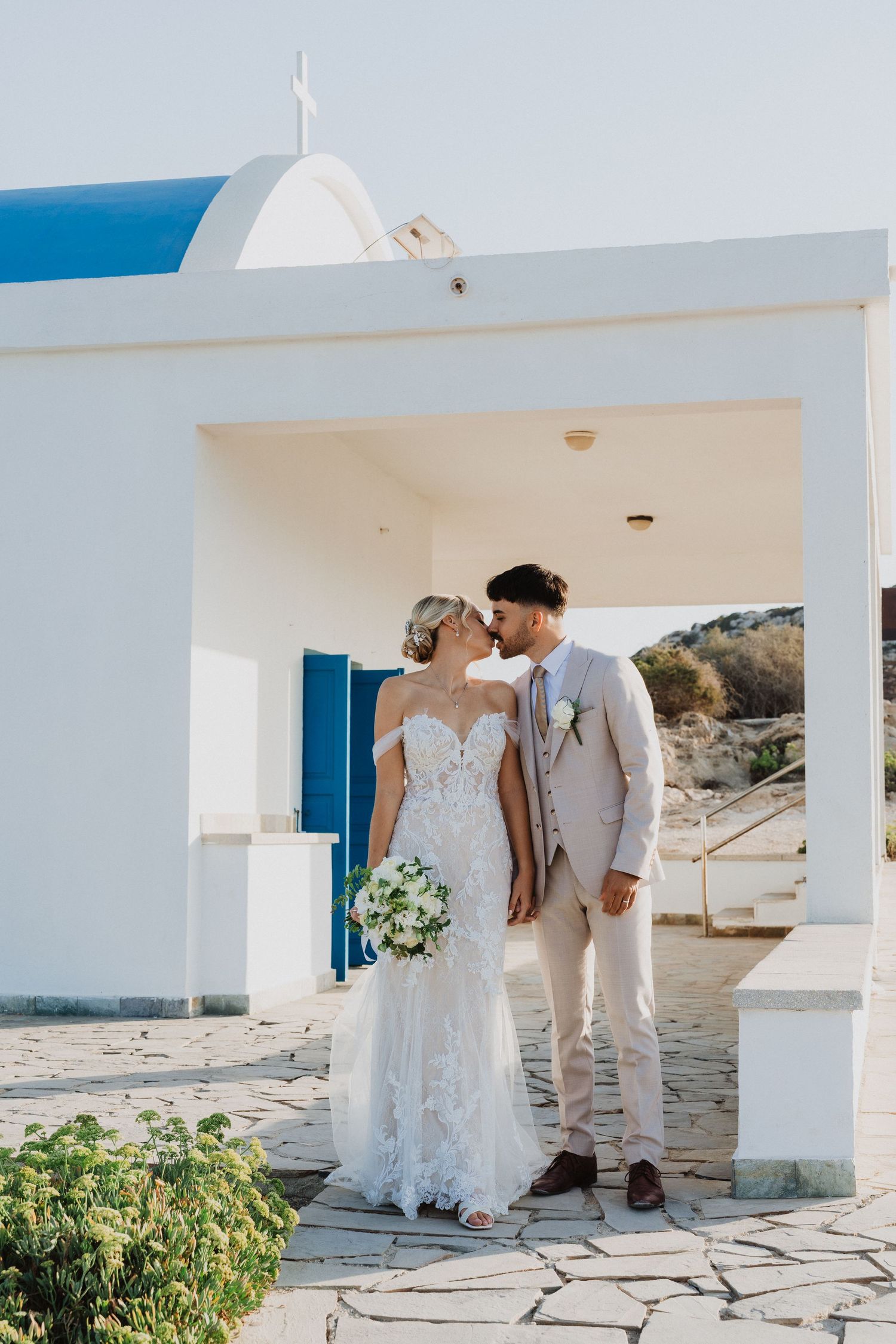 Elegant wedding photography session at a traditional Greek-style white building by the sea.