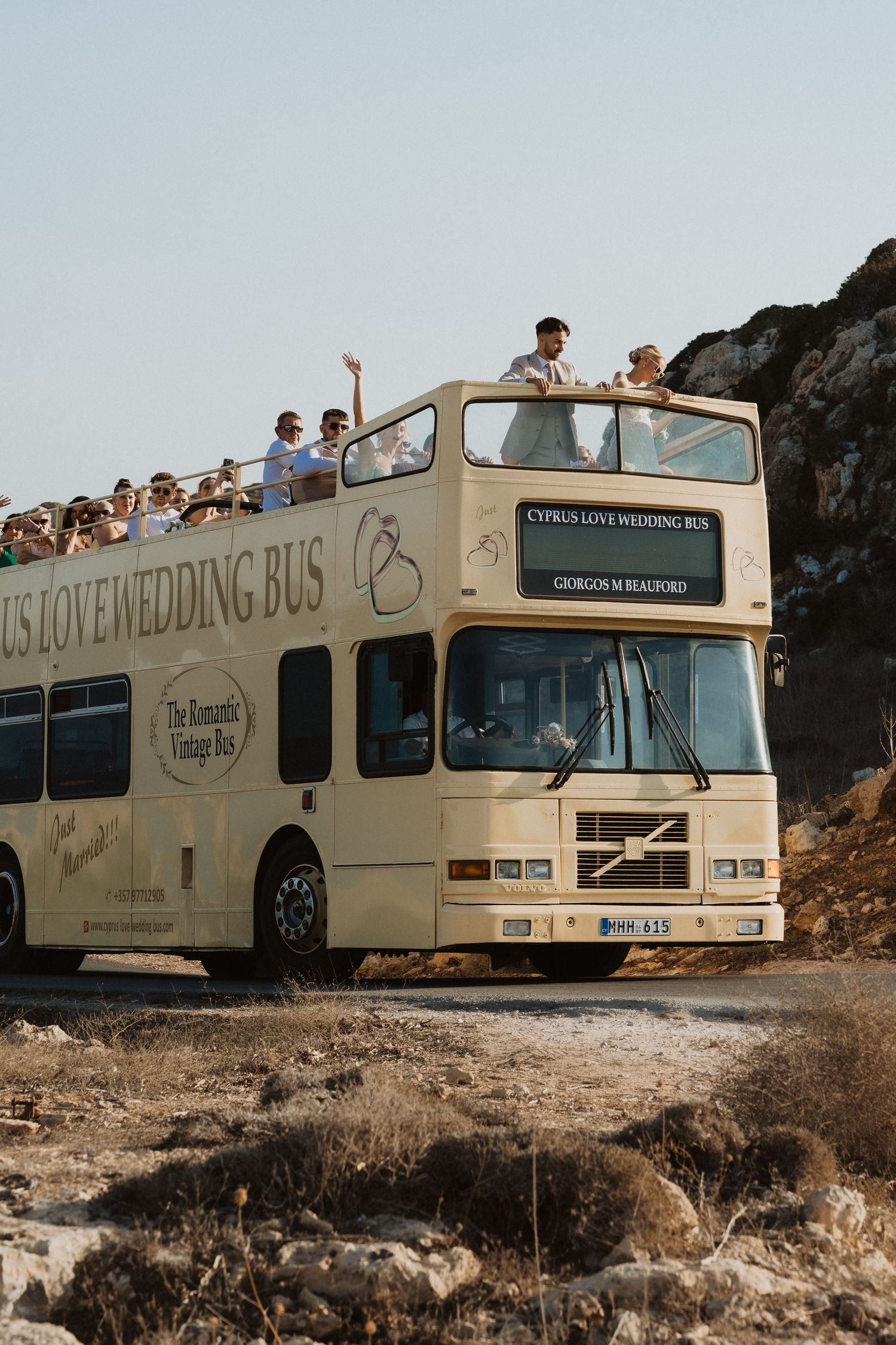 A cream colored Cyprus Love Wedding Bus photographed from different angles on a scenic route.