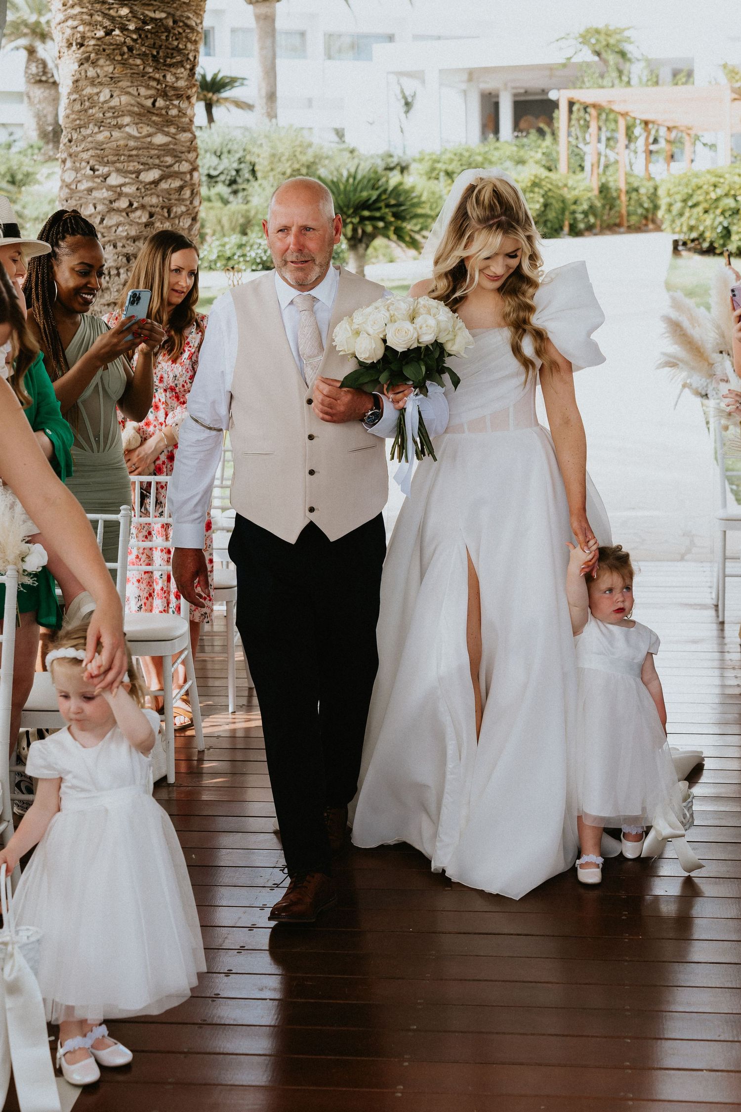 Wedding ceremony processional on tropical veranda with white floral decorations.