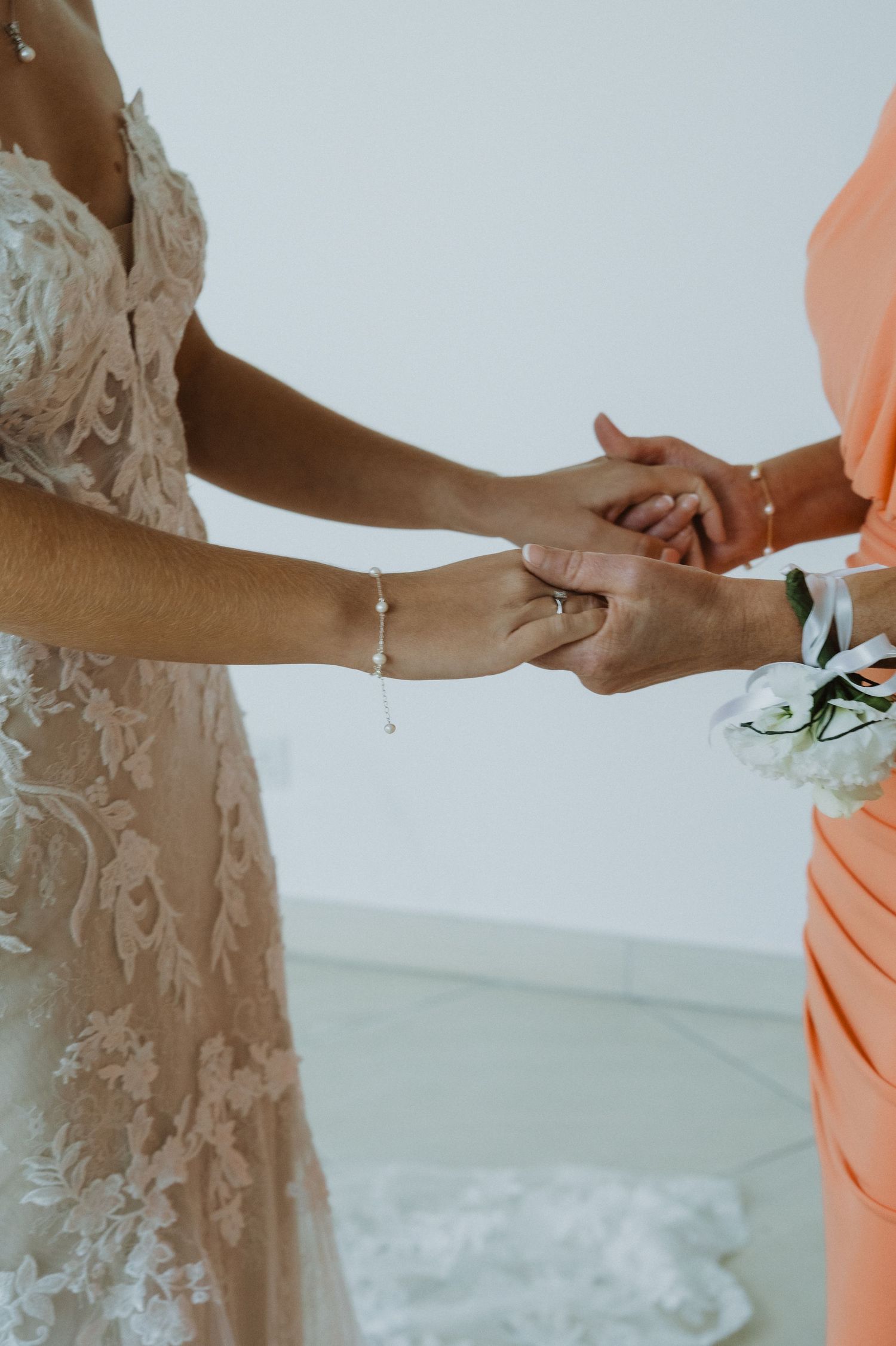 Detail shots of hands and wedding dress during bridal preparation.