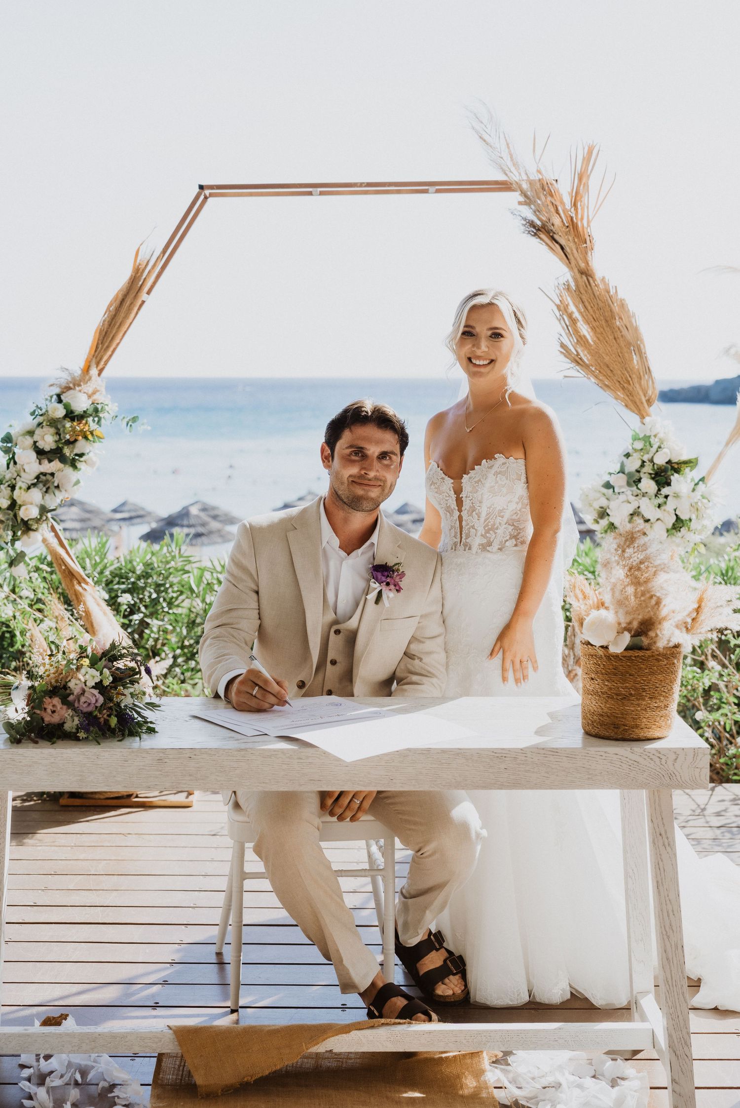 A couple signs their marriage certificate at an outdoor beach wedding ceremony.