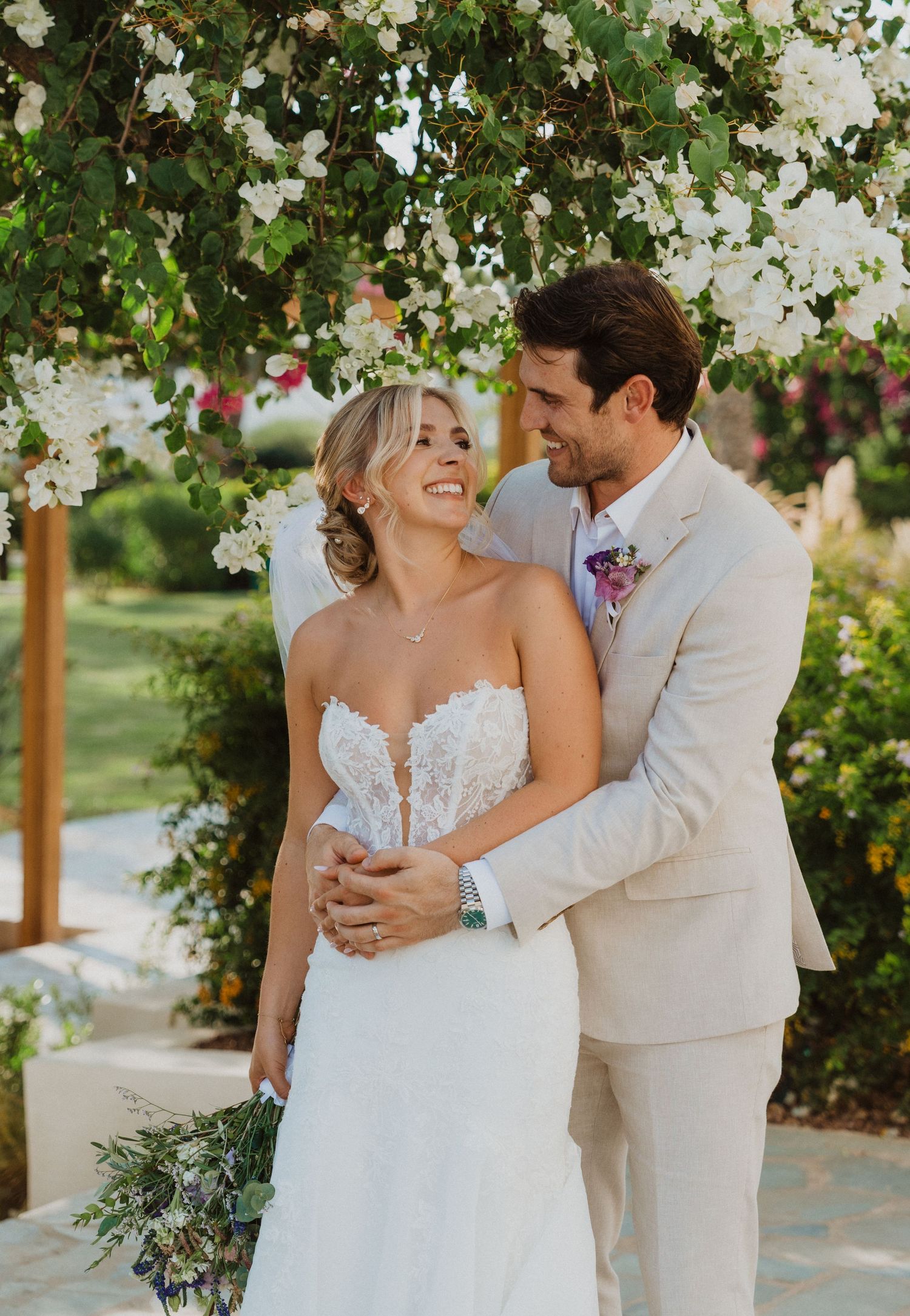 Joyful wedding portraits captured under flowering trees in outdoor garden venue.