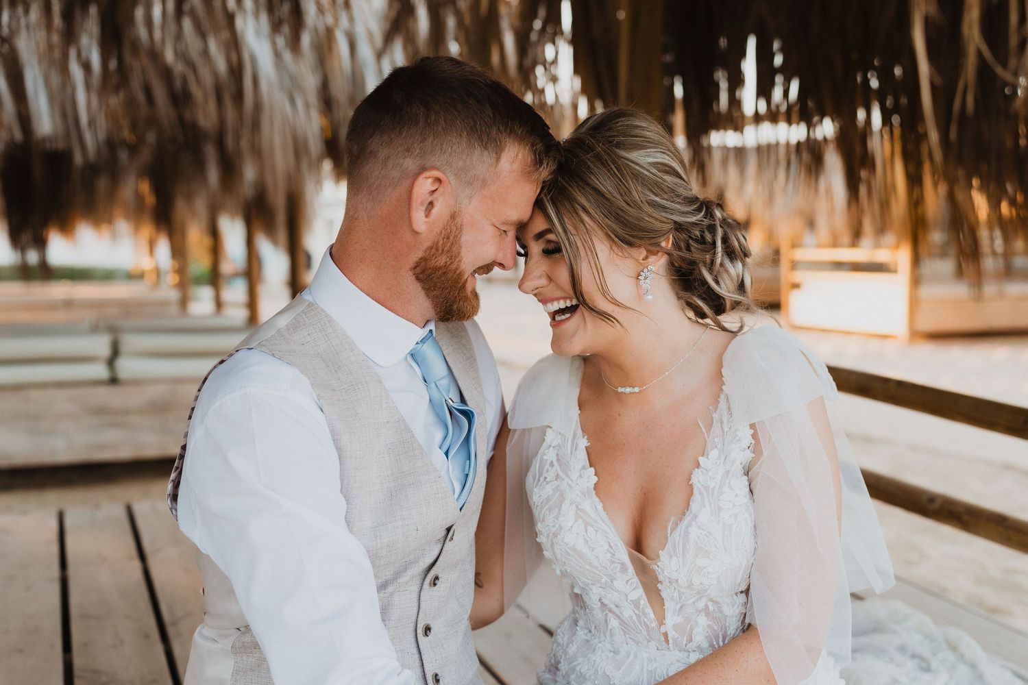 Close-up wedding photos of couple sharing intimate moments under palm frond roof.