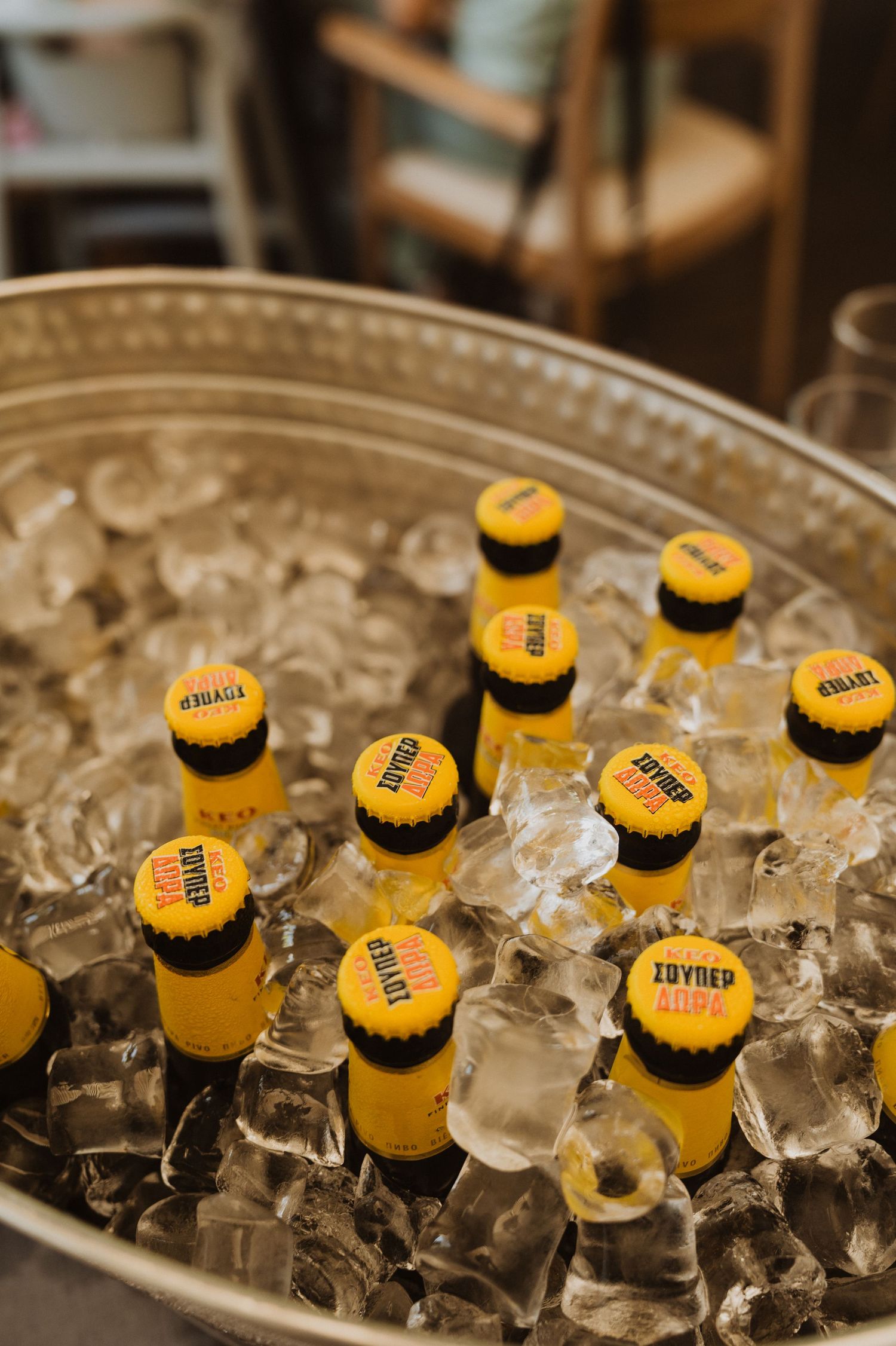 Yellow beer bottles chilling in a silver ice bucket filled with ice cubes at a party or event.