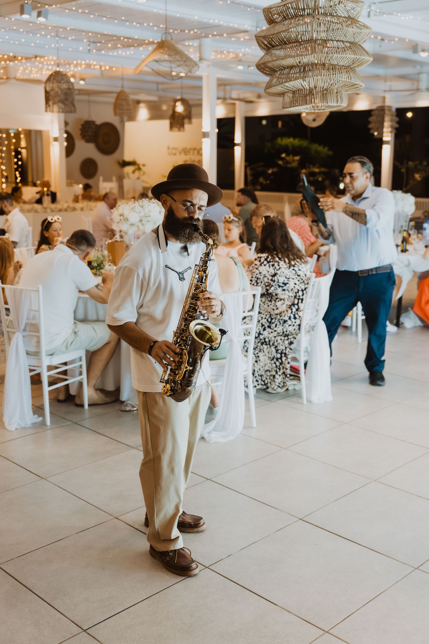 Wedding reception dance floor with guests dancing under crystal chandeliers and string lights.
