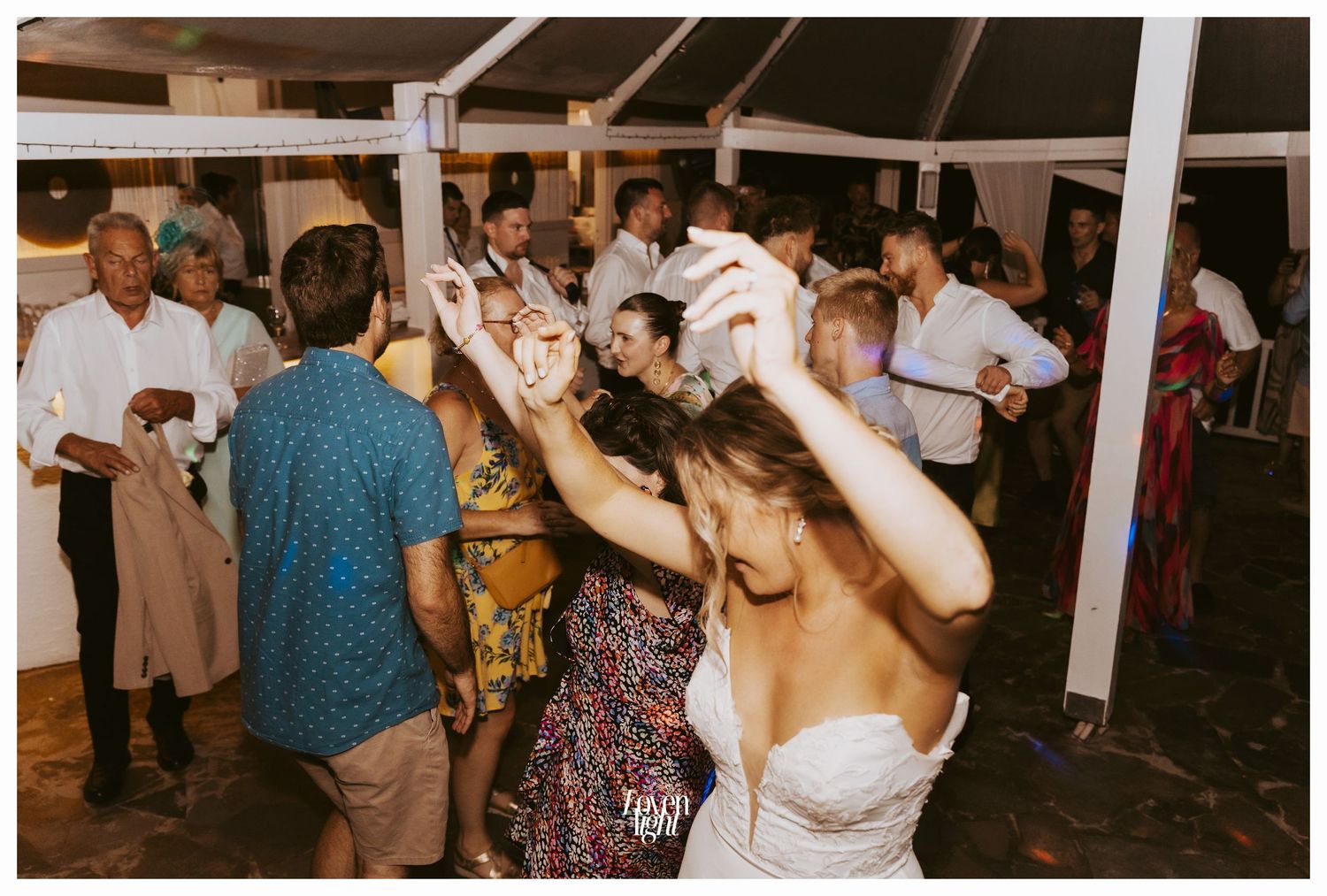 Wedding guests dancing and celebrating on the reception dance floor.