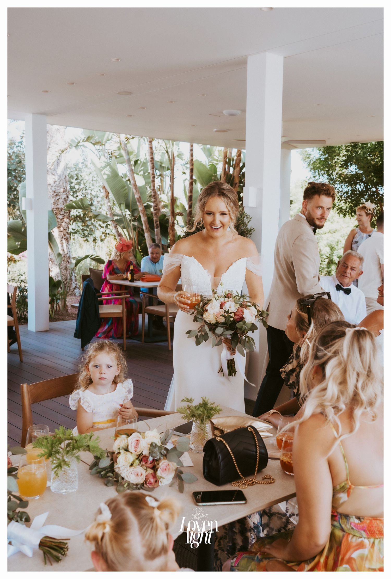 Wedding reception scene with table decorations and floral arrangements on a covered patio.
