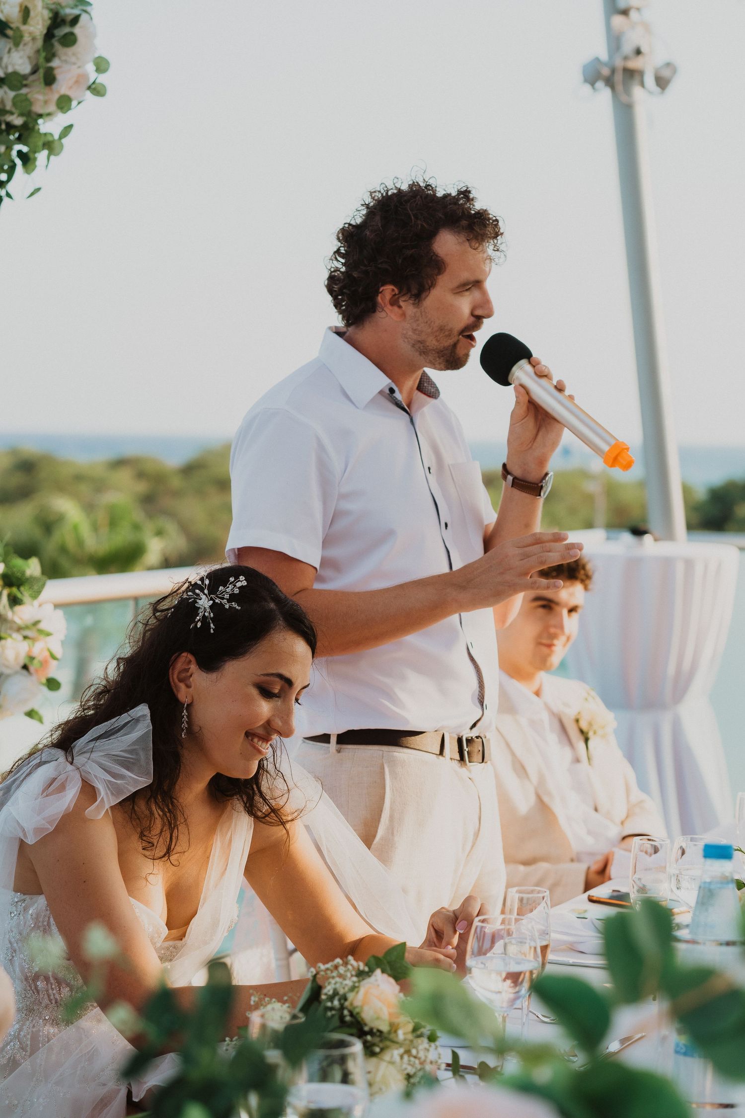 Wedding reception speech moment with seaside views and elegant table decorations.
