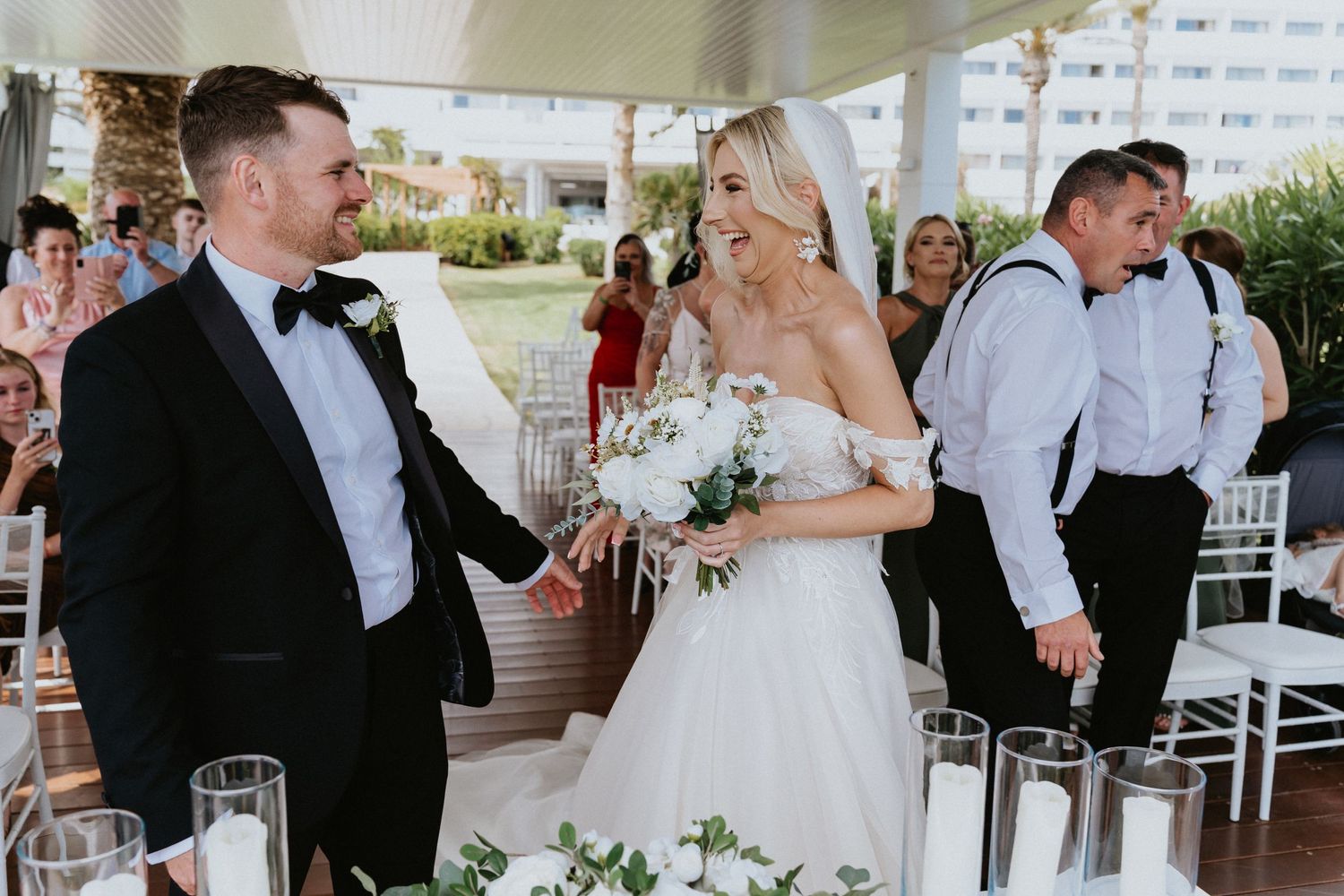 Elegant wedding reception scene with formal attire and white floral arrangements.