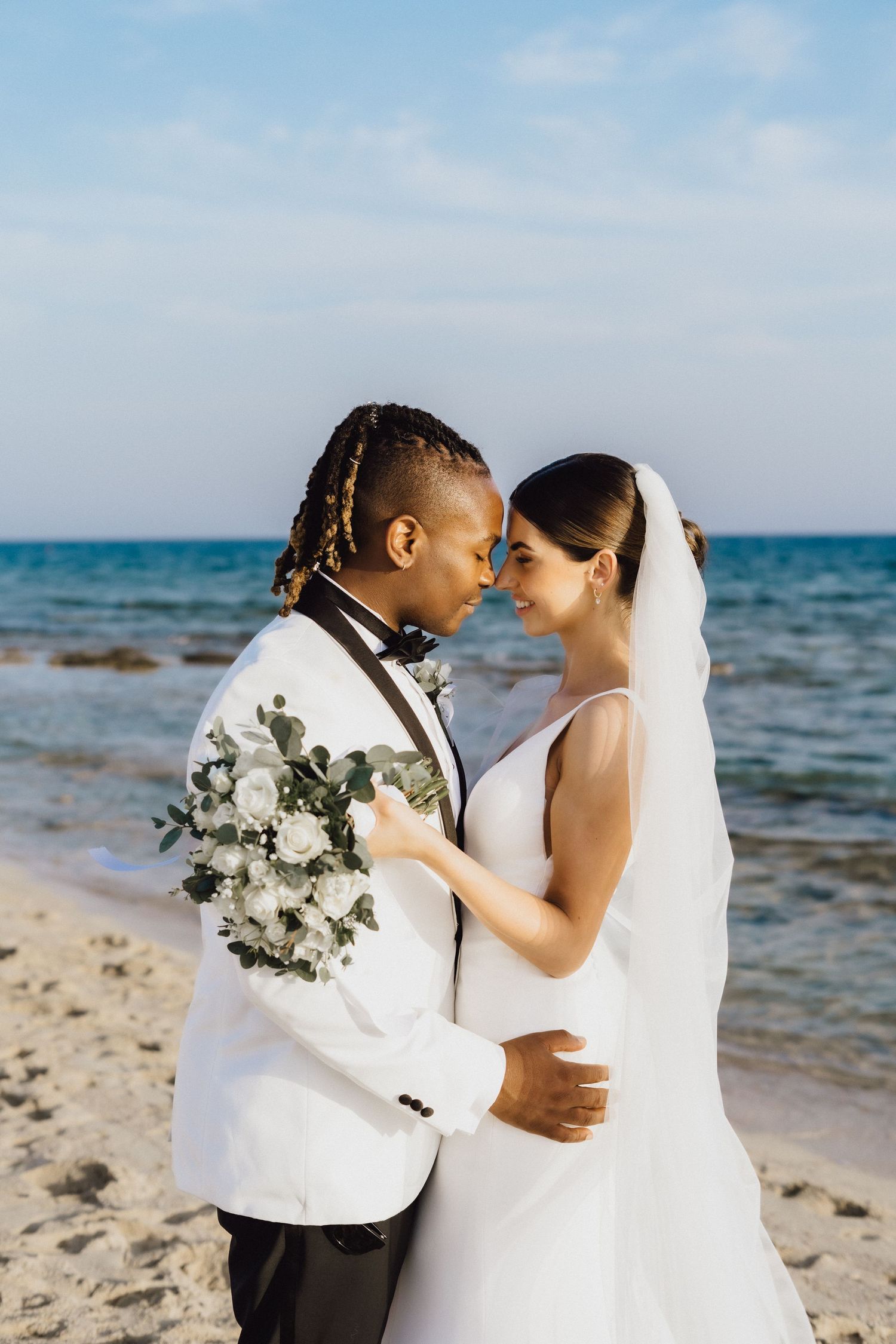 Romantic beachside wedding portrait with white floral bouquet.