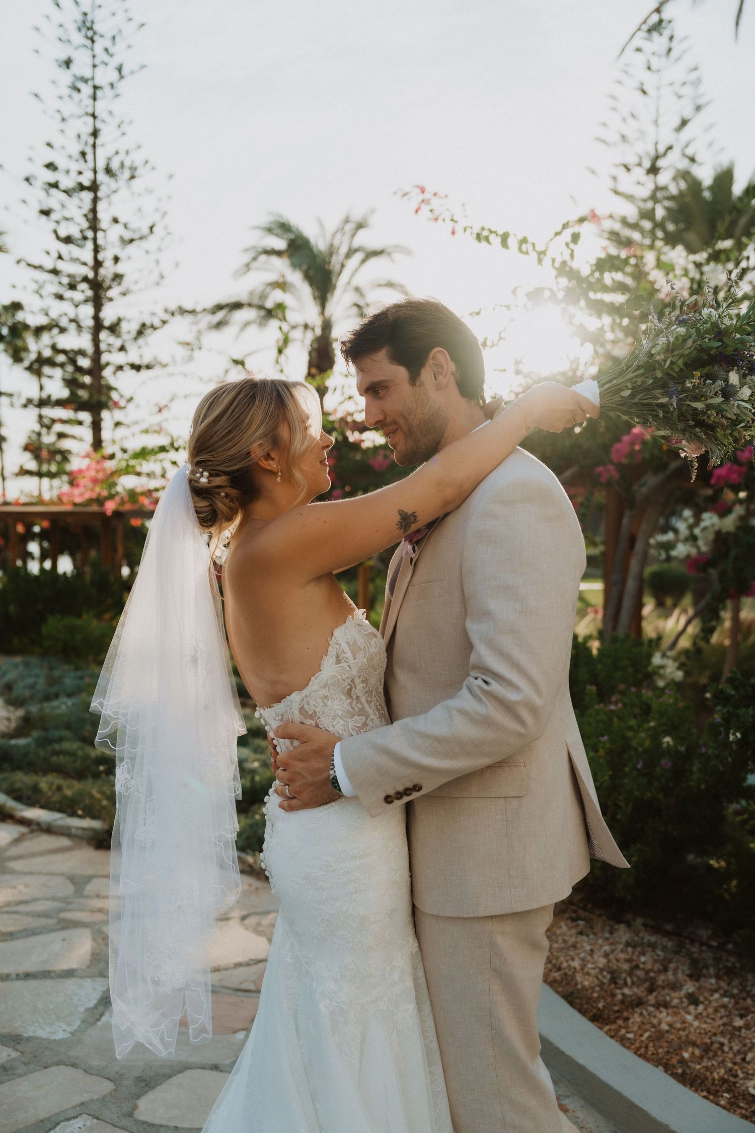 Intimate moment between bride and groom on a scenic garden pathway at sunset.