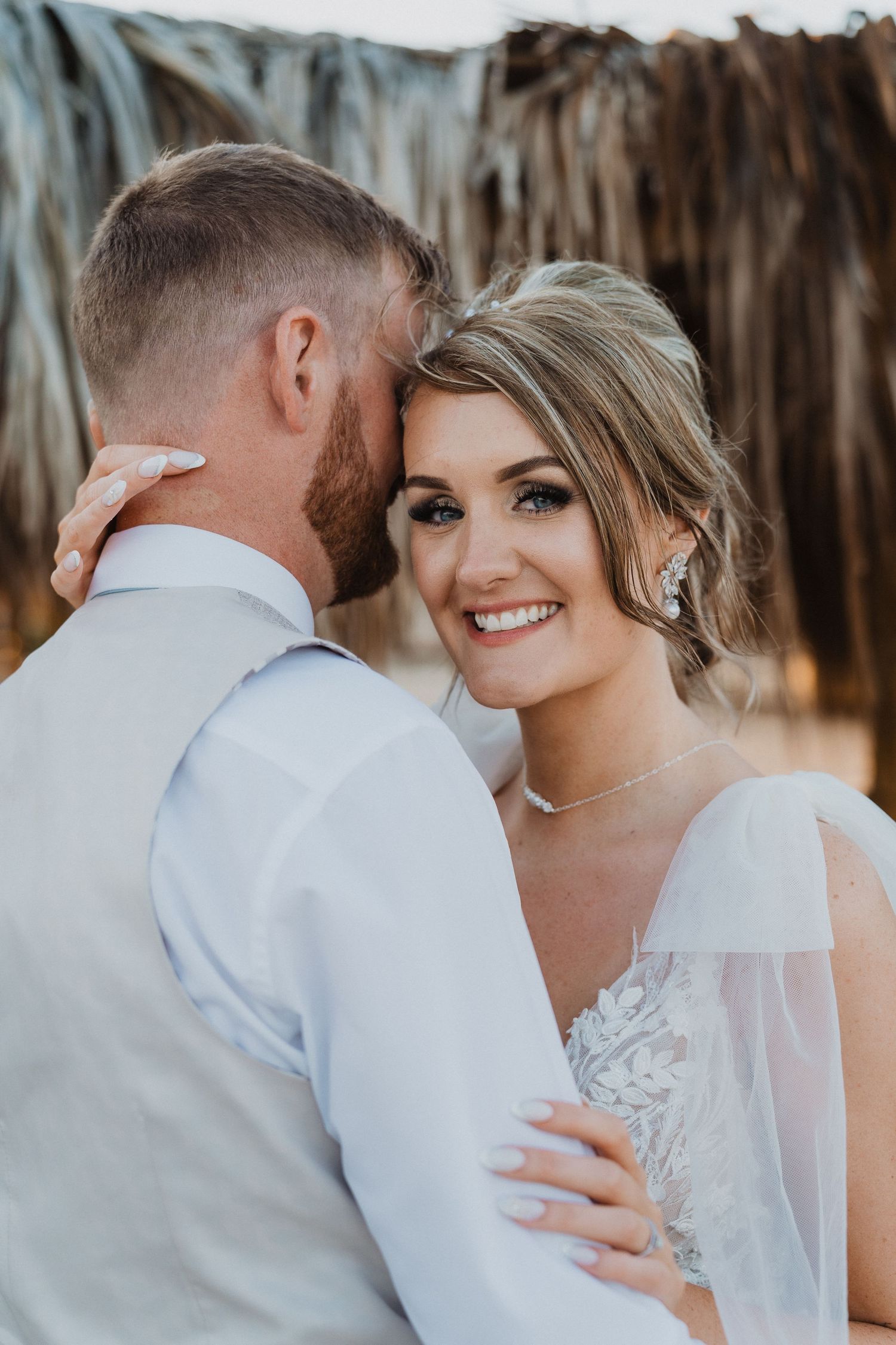 Series of romantic wedding portraits showing couple embracing under rustic beach shelter.