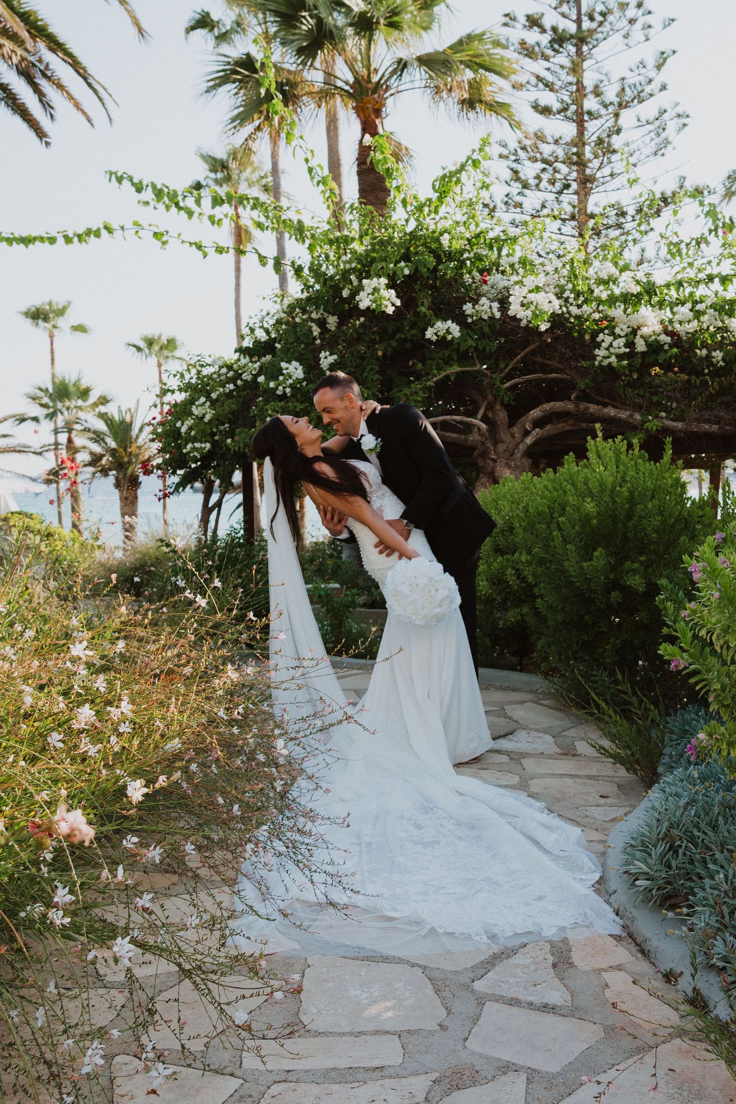 A romantic wedding photoshoot on a winding stone path with lush tropical landscaping.