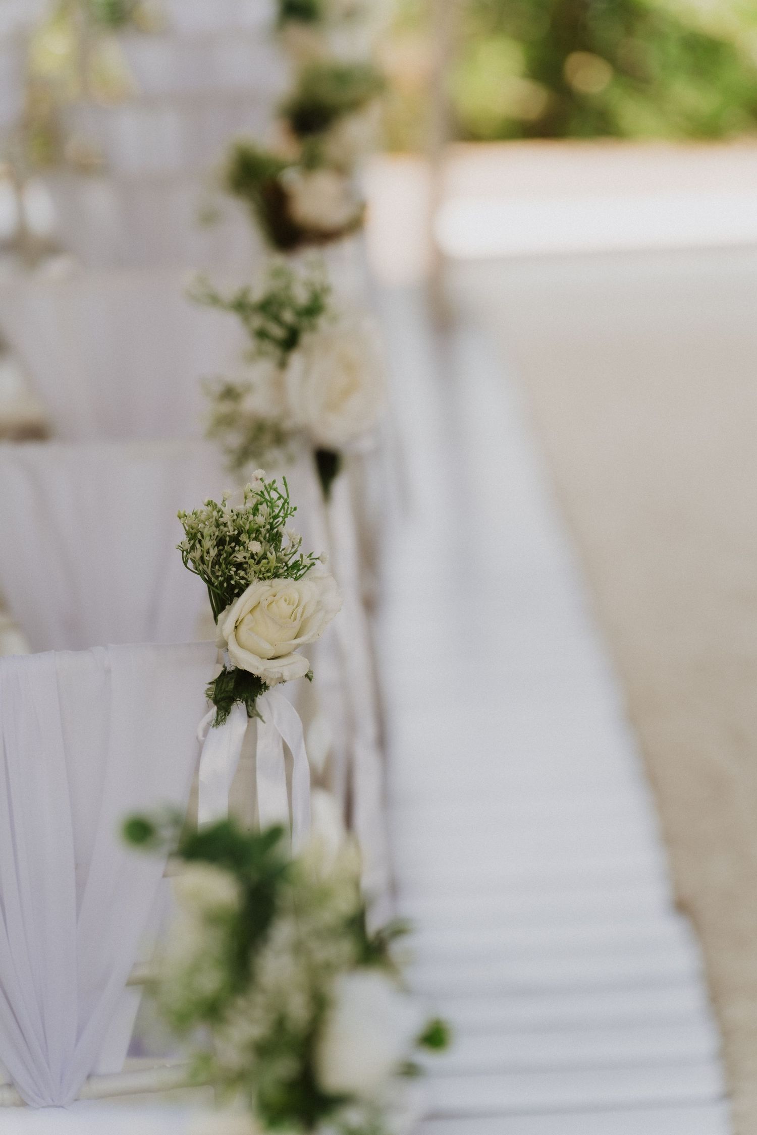 Elegant white floral arrangements with greenery accent wedding ceremony decor in a soft, romantic setting.